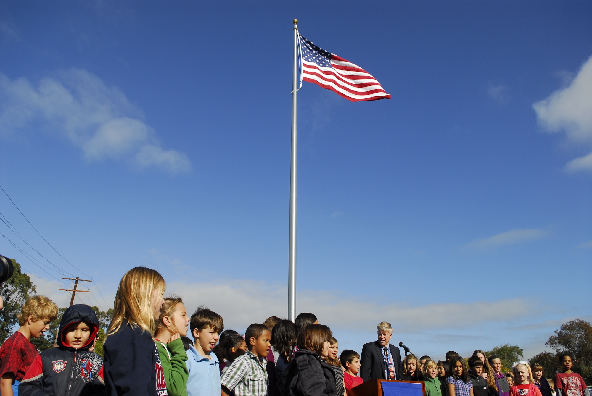 VANDENBERG AIR FORCE BASE, Calif. - Vandenberg's Crestview Elementary School students sing the school’s song with their principal, Ken Falk, to close out the school’s flagpole dedication ceremony here Friday, Nov. 18, 2011. The new flagpole replaced the school’s old one, which was in poor shape. (U.S. Air Force photo/2nd Lt. Austin Fallin)