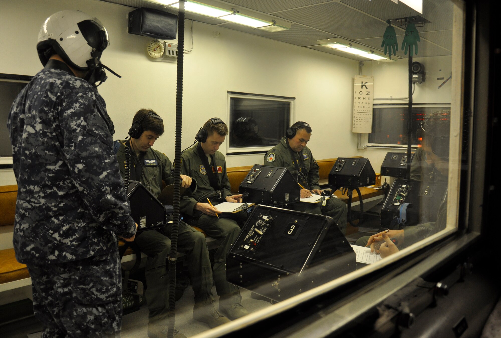 Capt. Joel Oyama, 446th Aeromedical Evacuation Squadron flight nurse (right), along with pilots from the 62nd Airlift Wing, perform written tasks in the high-altitude chamber at the Aviation Survival Training Center, Naval base Whidbey Island, Wash., Nov. 9, 2011. ASTC is where McChord Field aircrew members currently receive their high-altitude chamber refresher training. (U.S. Air Force photo/Master Sgt. Jake Chappelle)