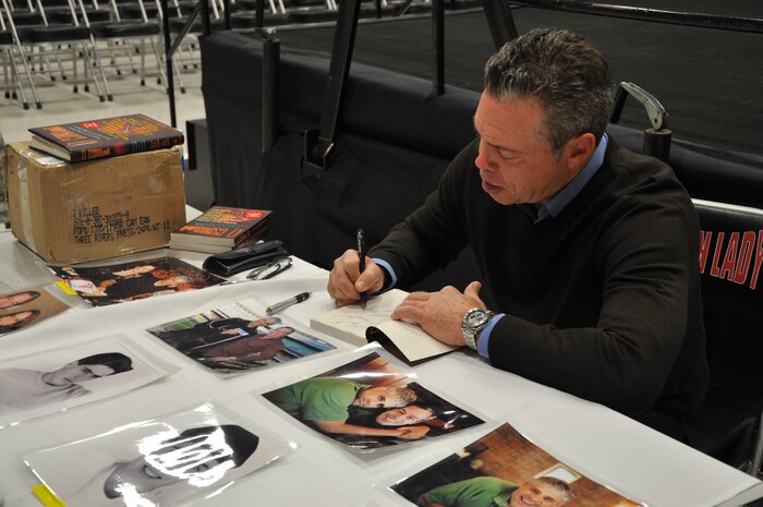 Comedian Bernie McGrenahan takes time after his show to autograph books and memorabilia for Airmen at Beale Air Force Base, Calif., Nov. 16, 2011. McGrenahan has performed at military bases for 15 years to promote alcohol awareness.  