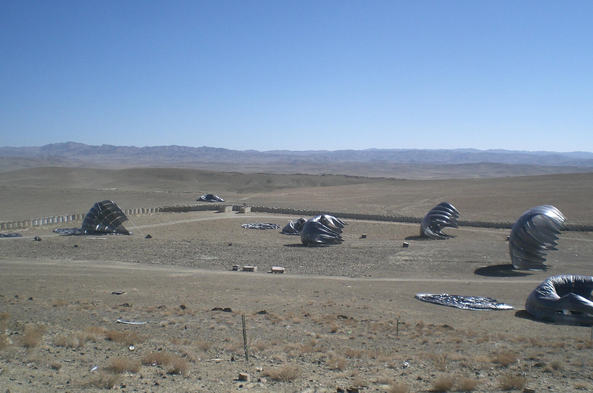 An emergency airdrop of fuel lands inside the newly created drop zone at firebase Atghar in Afghanistan’s Zabul Province, Nov. 18, 2010. Despite the small landing area, 19 of 20 bundles landed inside the firebase perimeter. The 20th bundle landed right outside the back gate, seen in the upper left. (Courtesy photo)