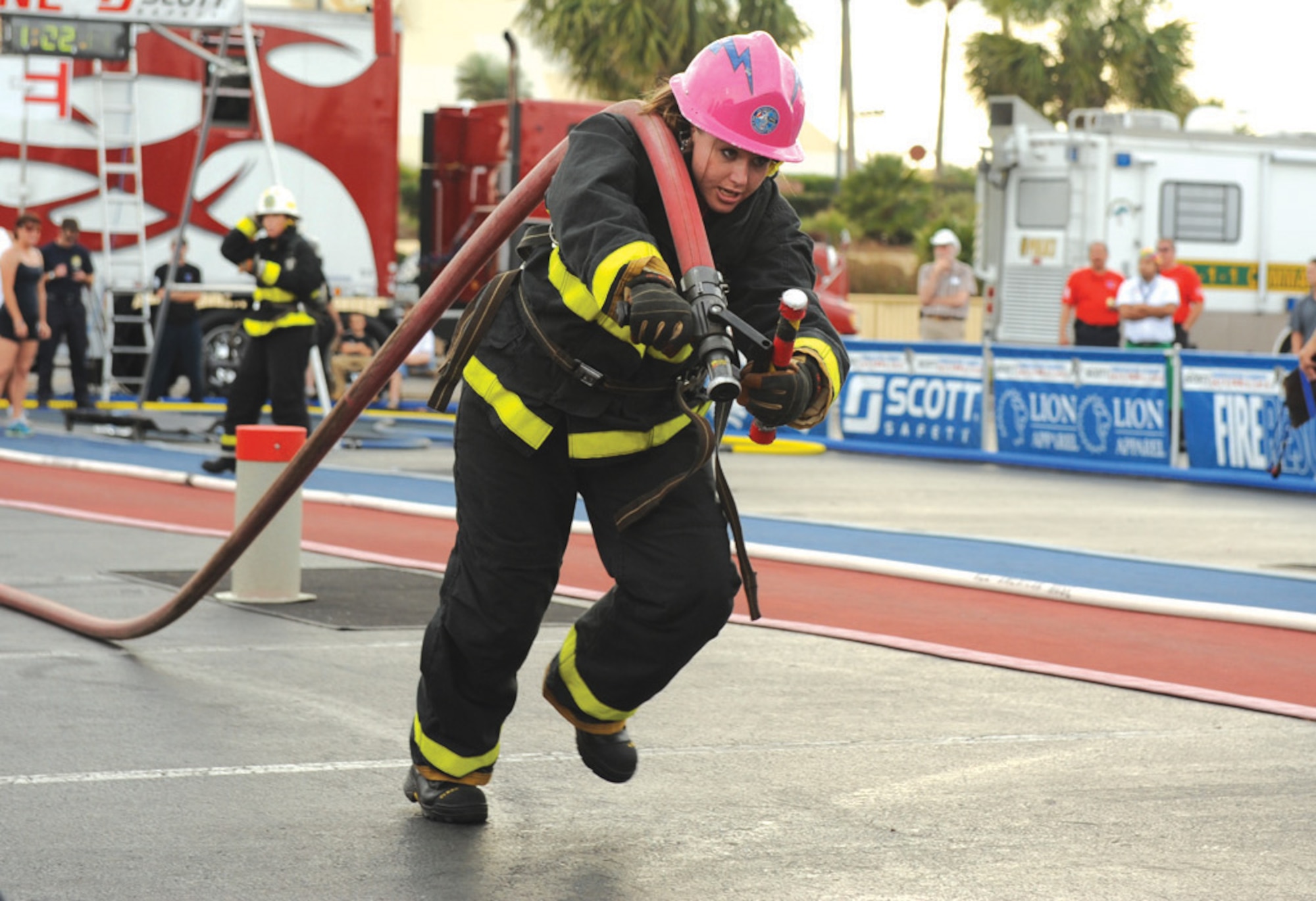 Senior Airman Jessica Morehouse, drags a loaded fire hose toward the saloon doors during the Firefighter Combat Challenge competition Wednesday.  Once she crosses the saloon doors, then she can hit the target with a stream of water to knock down the target and complete the fourth of five events on the course. Airman Morehouse is a founding member of the Fire Fembots, a combined Academy-Colorado Springs team of women firefighters who own both the world record time in their category and are three-time defending world champions.
(U.S. Air Force Photo/John Van Winkle)