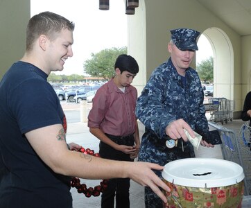 U.S. Navy Petty Officer 1st Class Clay Cowley (right), Defense Readiness Medical Training, Houston, with his son, Ian, donate money to Operation Warmheart Nov. 18 as Senior Airman Eddie Green (left), Air Force Personnel Center, takes a shift volunteering for the cause. (U.S. Air Force photo/Rich McFadden) (released)
