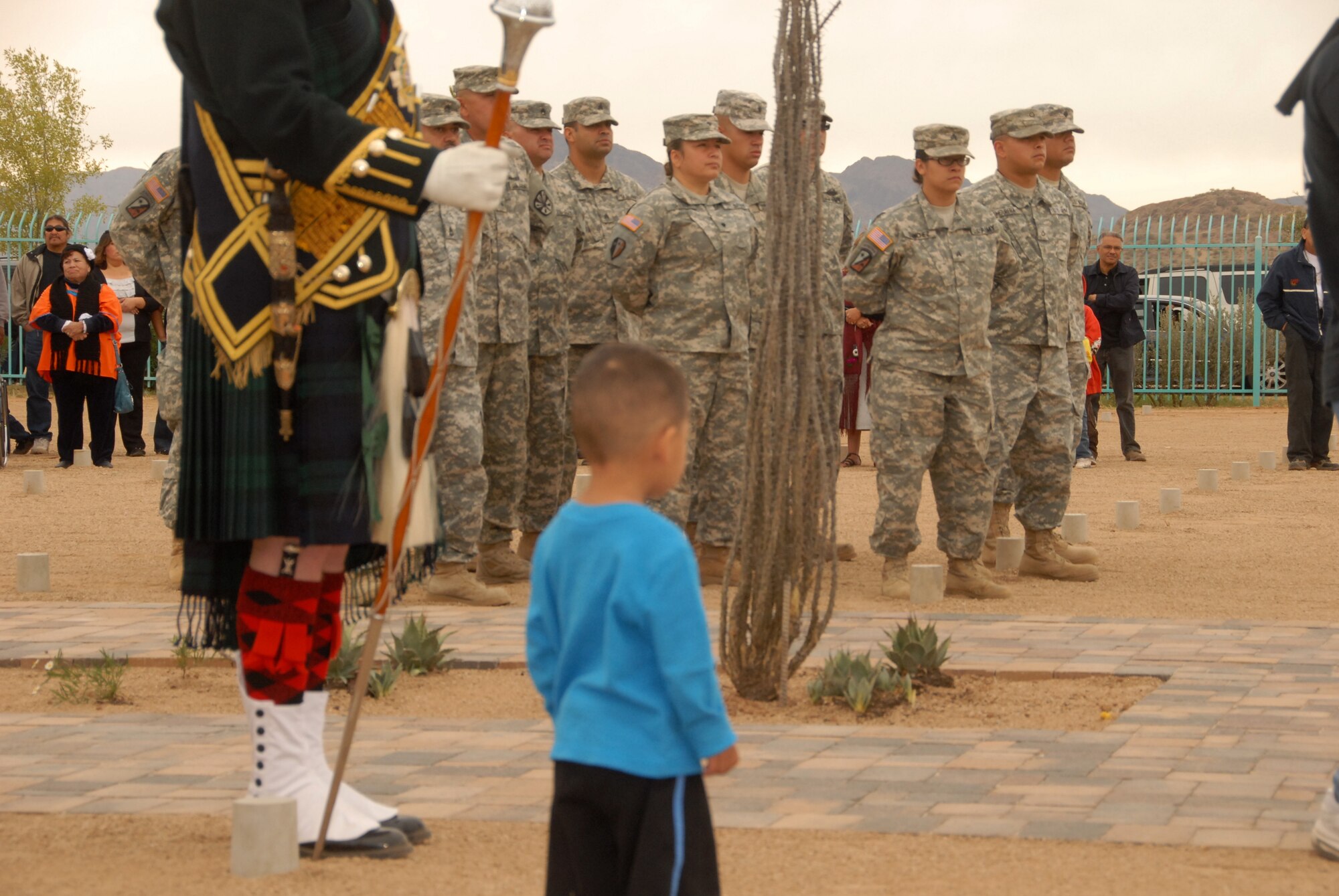 A child moves to get a closer look at Arizona citizen soldiers in formation during the opening ceremony of the Veterans Memorial at the Pasqua Yaqui Cemetery, Nov. 11. Soldiers from various units, including those serving on Operation Copper Cactus, volunteered their off duty time to support the community event. In attendance were local tribal leaders, representatives from veterans’ service organizations and local civic leaders. (U.S. Air Force photo/Master Sgt. Desiree Twombly)