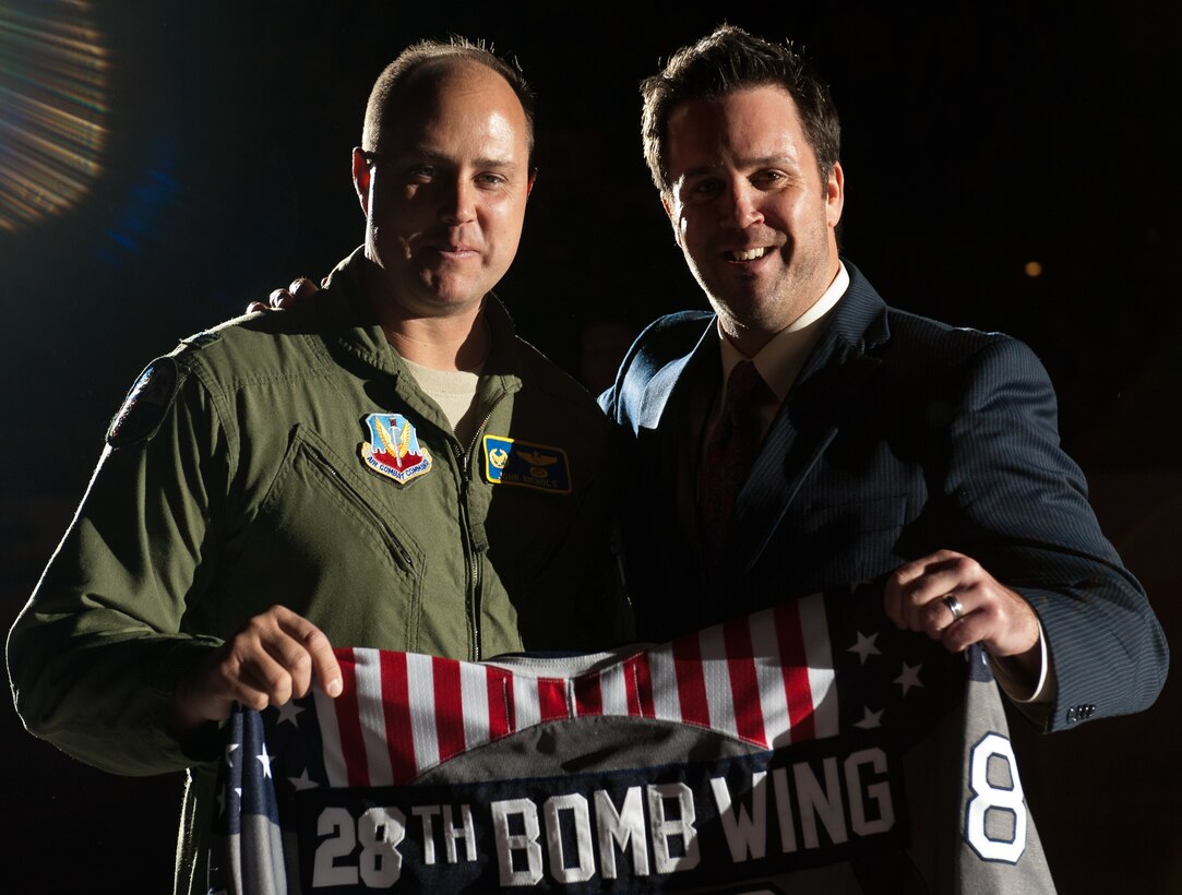 Col. John Nichols, 28th Operations Group commander, and Tim Hill, Rapid City Rush general manager, hold a patriotic themed hockey jersey before the Rapid City Rush hockey game at the Rushmore Plaza Civic Center in Rapid City, S.D., Nov. 11, 2011. Col. Nichols accepted the jersey on behalf of Ellsworth Air Force Base during the Rush hockey team’s Veterans Day military appreciation game as a token of gratitude to those who have served and currently serve in the Unites States military.  (U.S. Air Force photo by Airman 1st Class Kate Thornton/Released) 