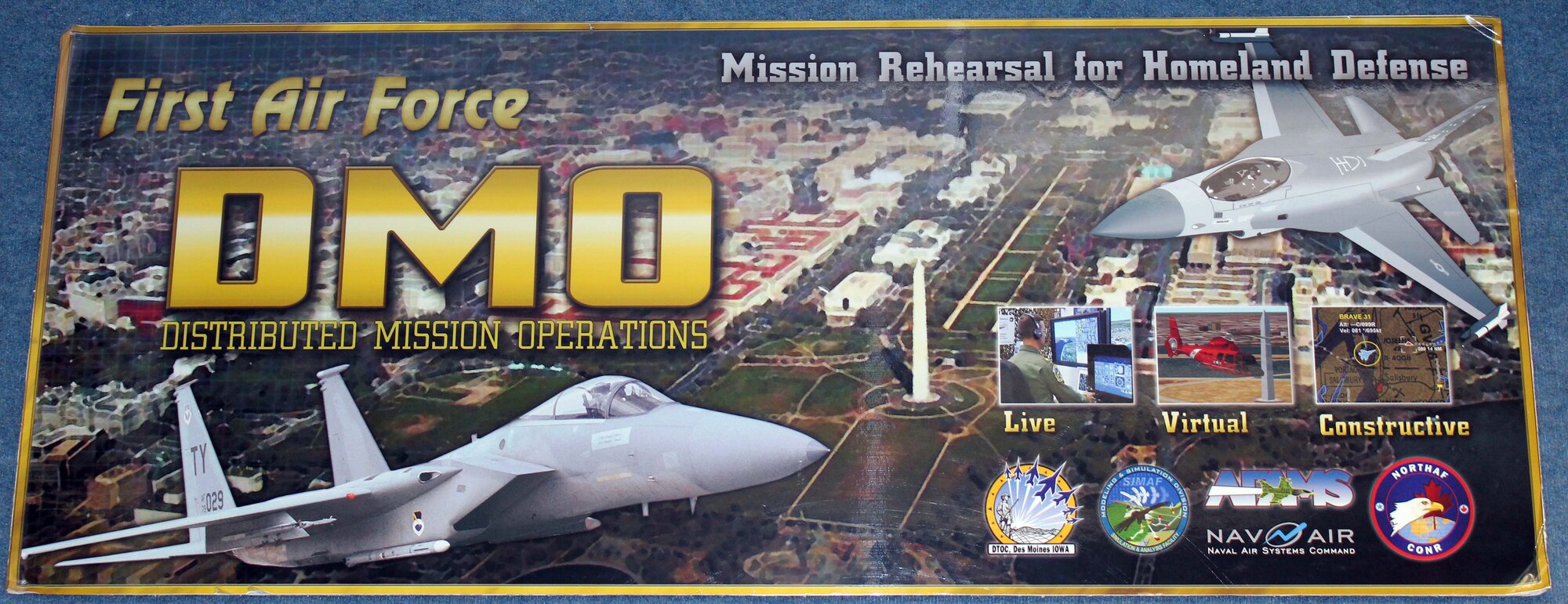 This sign hangs in Air Forces Northern’s Distributed Mission Operations lab in the 601st Air and Space Operations Center, highlighting DMO’s capabilities. DMO is a system of inter-connected simulators that allows warfighters from across the U.S. and Canada to participate simultaneously in the same live scenario. (U.S. Air Force Photo by Angela Pope)