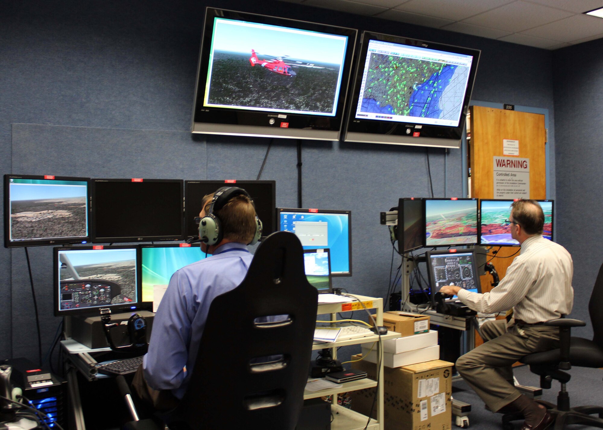 Dale Carson (left) and Larry Christie, contractors with Air Forces Northern’s Distributed Mission Operations system, fly aircraft simulators during a scenario Nov. 16. DMO is a system of inter-connected simulators that allows warfighters from across the U.S. and Canada to participate simultaneously in the same live scenario. (U.S. Air Force Photo by Angela Pope) 