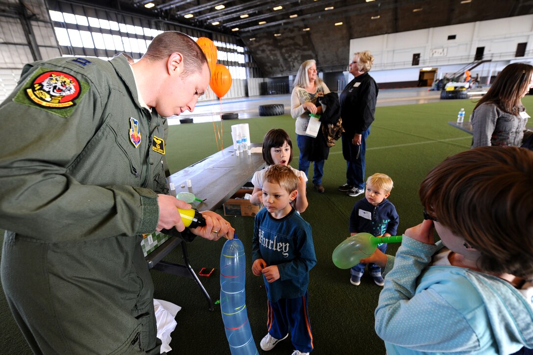 Capt. Adam Flaherty, 37th Bomb Squadron flight commander, blows up balloons for children during the Big Brothers and Big Sisters of the Black Hills event held at the Pride Hangar on Ellsworth Air Force Base, S.D., Nov. 12, 2011. The event was a chance for Air Force members to reach out and mentor and provide fun to young children by demonstrating propulsion with balloons and aerodynamics with paper planes. (U.S. Air Force photo by Airman 1st Class Zachary Hada/Released)