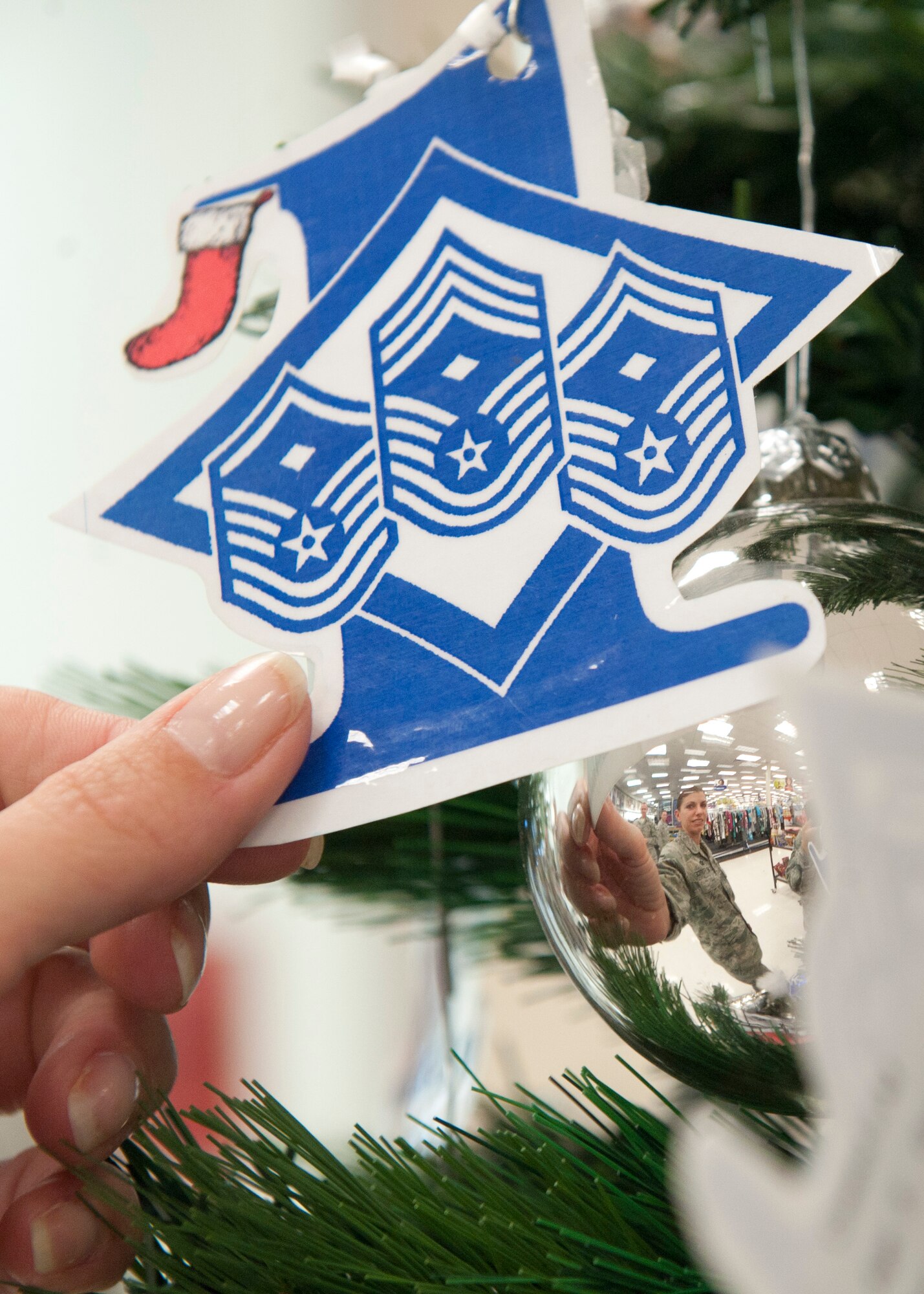 HOLLOMAN AIR FORCE BASE, N.M. -- U.S Air Force Master Sgt. Tamara Kissinger, 49th Communication Squadron first sergeant, hangs a Diamond Tree ornament Nov. 10, 2011, at the Exchange. The Diamond Tree, sponsored by the Holloman First Sergeant Council, contains over 100 ornaments that provide the name of a child, clothing size and gift idea for those who would like to help children of military families who are struggling financially. (U.S. Air Force photo by Senior Airman Veronica Stamps/Released)