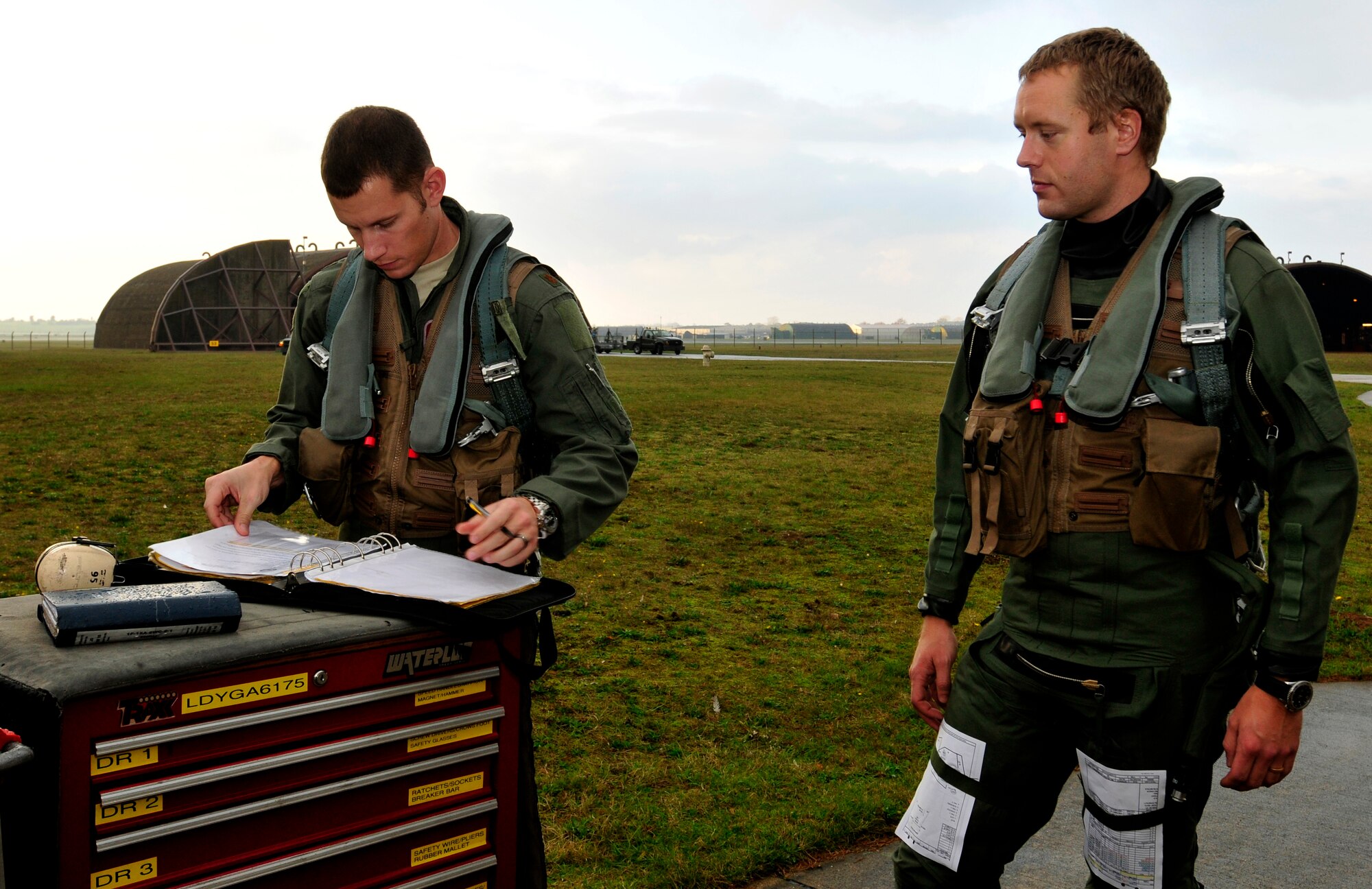 ROYAL AIR FORCE LAKENHEATH, England - U.S. Air Force Maj. Mike Conrad, 493rd Fighter Squadron pilot, (left) checks aircraft forms as Swedish Air Force Capt. Fredrik Bergstrom, 211th Fighter Squadron, watches prior to take-off, Nov. 17, 2011. This is Bergstrom's first time in a foreign aircraft. Members from the SAF and the 48th Fighter Wing trained together to increase their interoperability and gather experience with foreign aircraft. (U.S. Air Force photo by Senior Airman Tiffany M. Deuel)