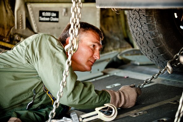 Senior Master Sgt. John Siebert, a loadmaster from the 165th Airlift Squadron, uses chains to secure a truck and trailer packed with rescue gear to a Kentucky Air Guard C-130 as Airmen prepare to deploy Sept. 28, 2011, from Louisville, Ky., to Joint Base McGuire-Dix-Lakehurst, N.J., where they were expected to stage for rescue operations in the aftermath of Hurricane Irene. The deployment was called off just prior to the Airmen's departure when damage from Irene was found to be less extensive than anticipated. (U.S. Air Force photo by Maj. Dale Greer)