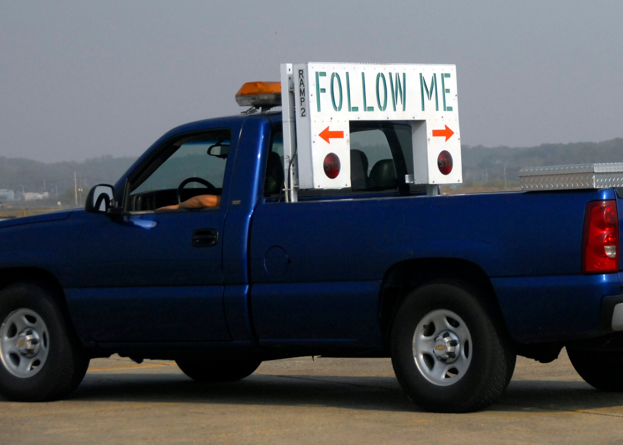 Two Transient Alert team members await a visiting aircraft on the flightline at Osan AB. The “Follow Me” sign on back of a pickup truck is the hallmark of the Transient Alert. (U.S. Air Force photos/ 1st Lt. Sara Greco)