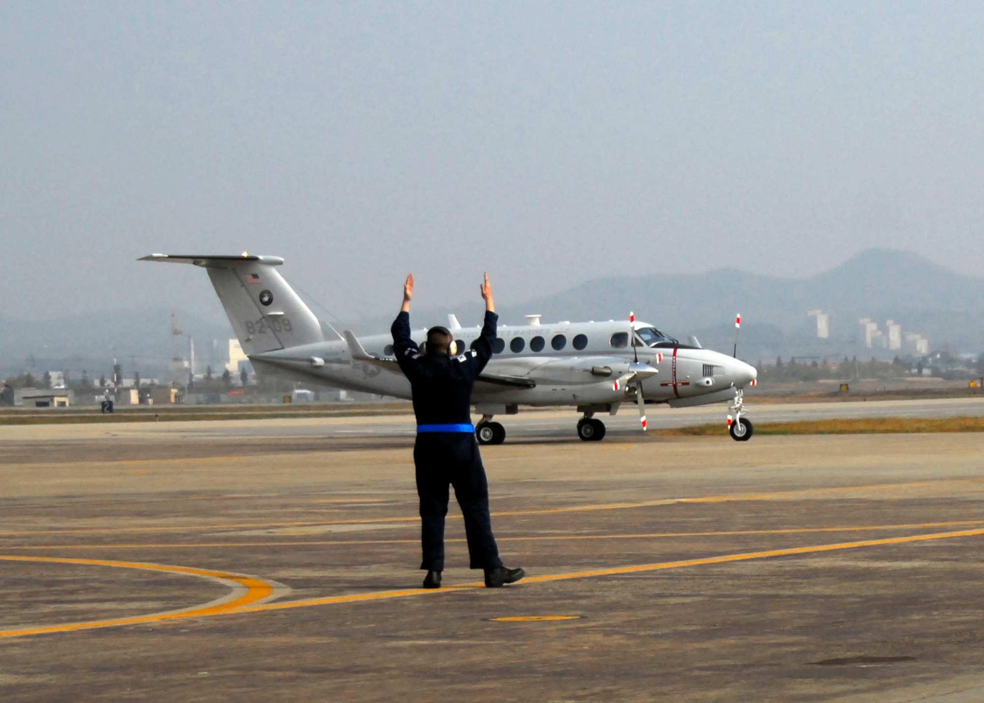 Two Transient Alert team members await a visiting aircraft on the flightline at Osan AB. The “Follow Me” sign on back of a pickup truck is the hallmark of the Transient Alert. (U.S. Air Force photos/ 1st Lt. Sara Greco)