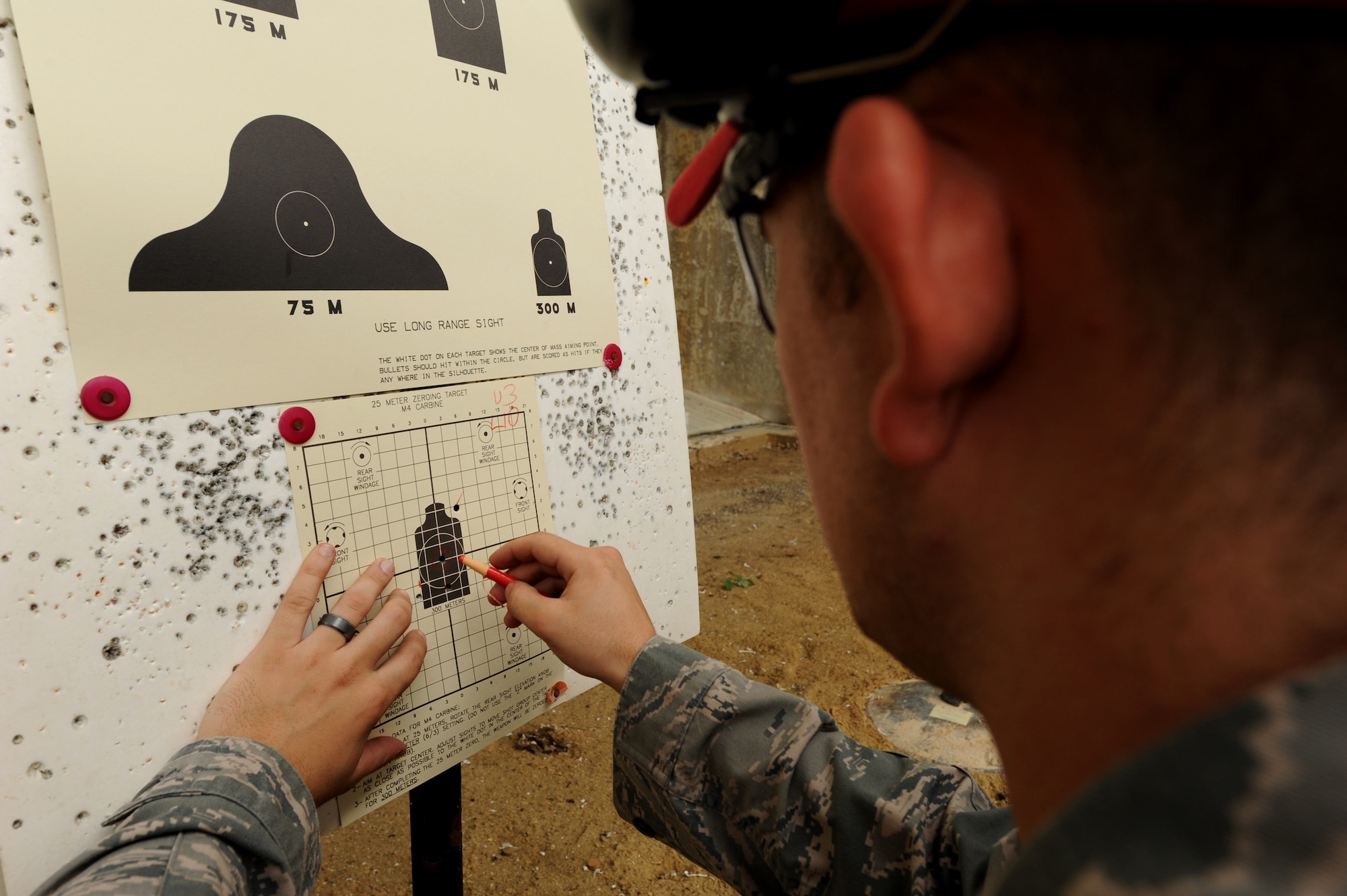 U.S. Air Force Senior Airman Skyler Thacker, 18th Security Forces Squadron combat arms instructor, indicates sight corrections on the zeroing target during the new weapons qualifications course at Kadena Air Base, Japan, Nov. 8, 2011. Beginning Dec.1, all Airmen are required to perform in the modernized rifle qualification course which comprises movement while engaging targets to better train and equip Airmen for today's fight. (U.S. Air Force photo by Senior Airman Jarvie Z. Wallace/Released) 

