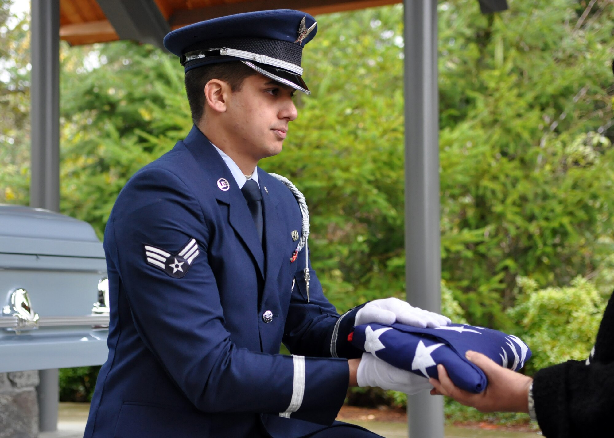 Senior Airman Joshua Hutton gives a folded American flag to the daughter of a deceased Airman during a funeral Nov. 18, 2011, at Tahoma National Cemetery in Kent, Wash. (U.S. Air Force photo/Airman 1st Class Leah Young)