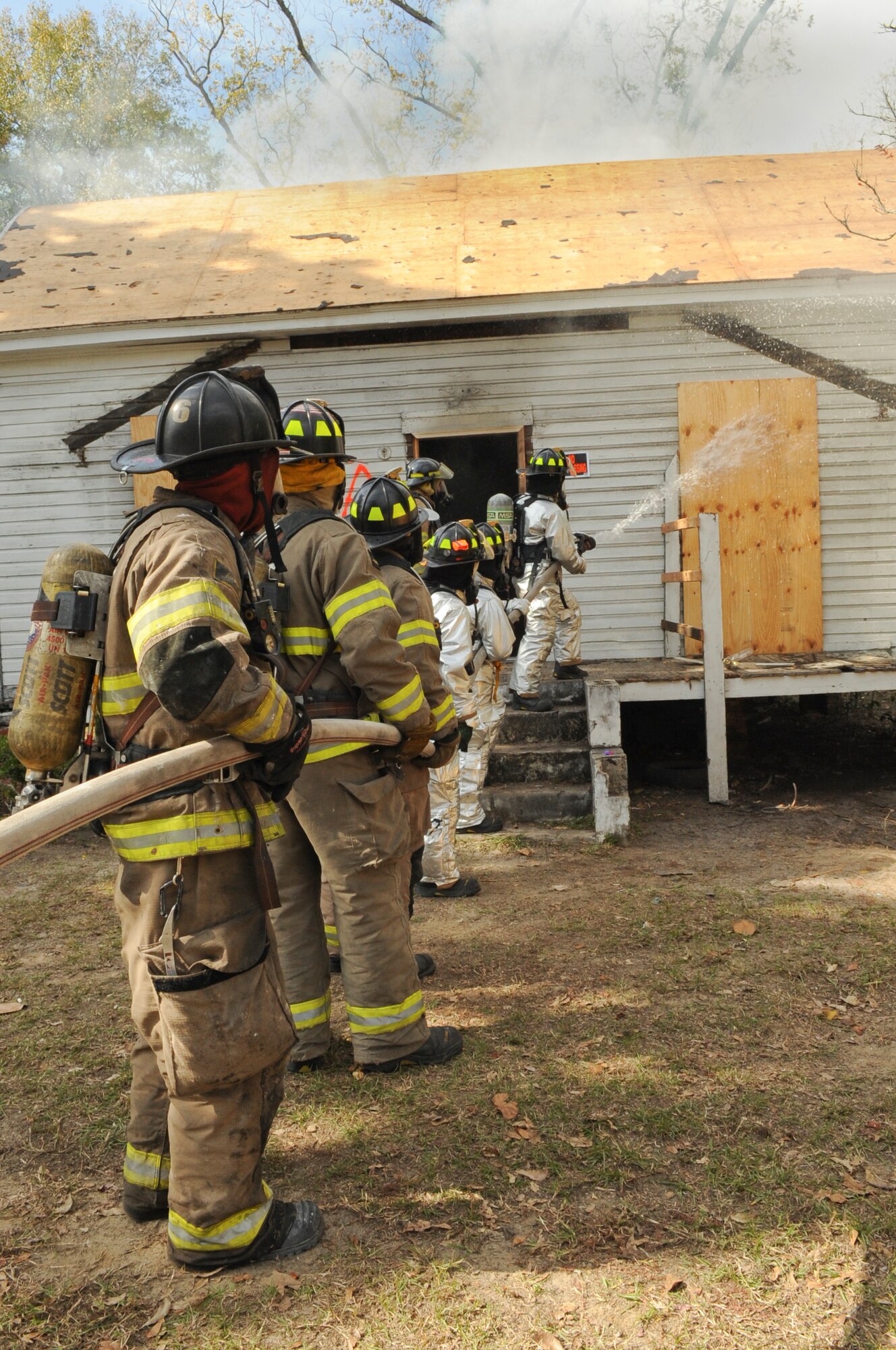 Members of the 23rd Civil Engineer Squadron and Valdosta Fire Department team up to extinguish a fire during live-fire training in Valdosta, Ga., Nov. 15, 2011.  The training gave the 23rd CES experience in dealing with house fires containing conditions they’ve never seen or practiced on. (U.S. Air Force photo by Airman 1st Class Olivia Dominique/Released) 