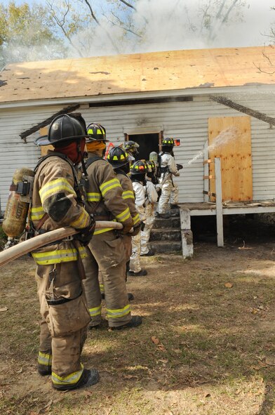 Members of the 23rd Civil Engineer Squadron and Valdosta Fire Department team up to extinguish a fire during live-fire training in Valdosta, Ga., Nov. 15, 2011.  The training gave the 23rd CES experience in dealing with house fires containing conditions they’ve never seen or practiced on. (U.S. Air Force photo by Airman 1st Class Olivia Dominique/Released) 