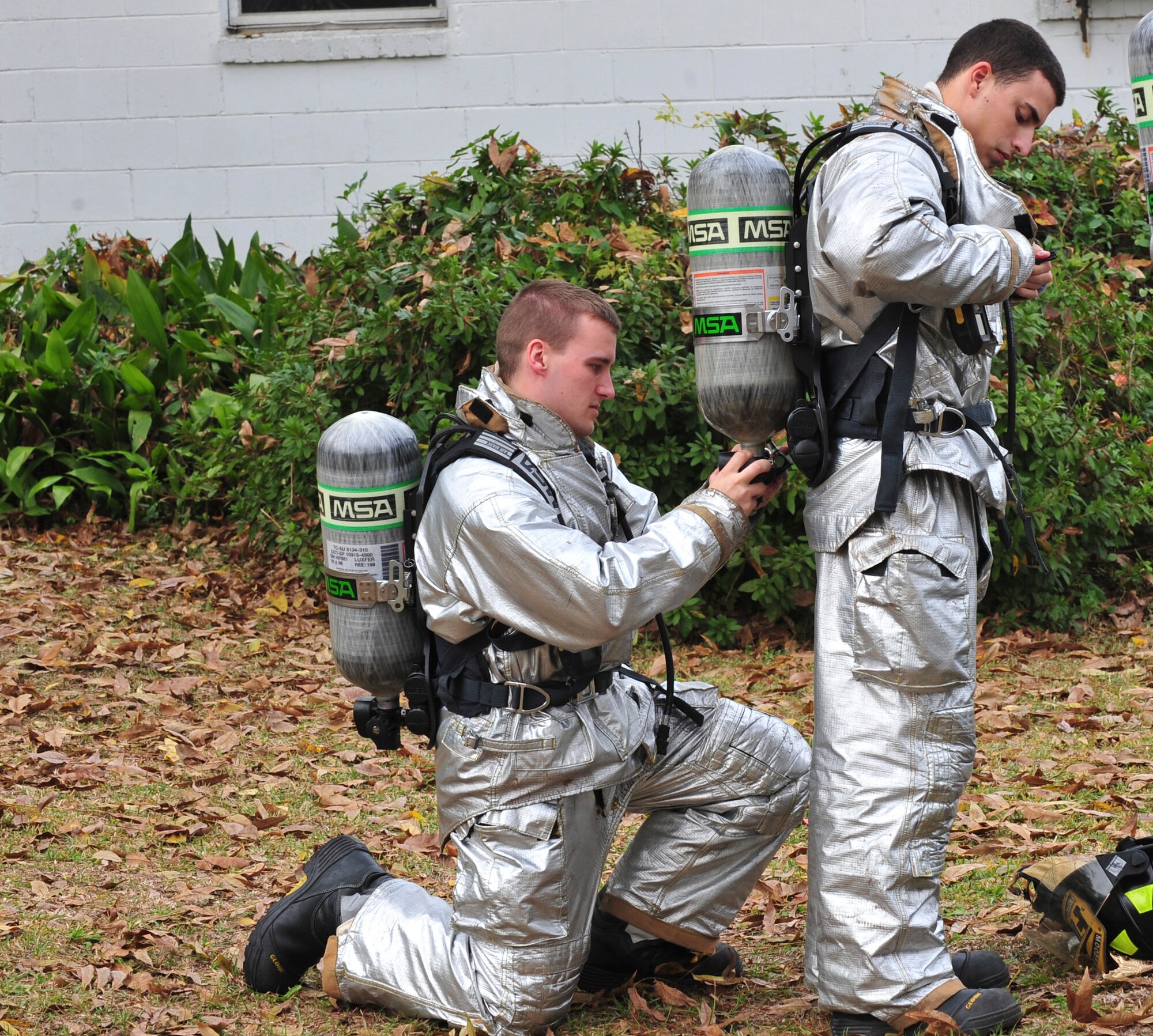 U.S. Air Force Airmen 1st Class Joseph Bagnasco, left, and Vincent Migliorino, 23rd Civil Engineer Squadron firefighters from Moody Air Force Base, Ga., check each other’s gear before entering a burning house during joint live-fire training with the Valdosta Fire Department in Valdosta, Ga., Nov. 15, 2011. It was the Airmen’s first time training in a live house fire. The training helped them identify and experience conditions normally not seen during a routine training session. (U.S. Air Force photo by Staff Sgt. Stephanie Mancha/Released)