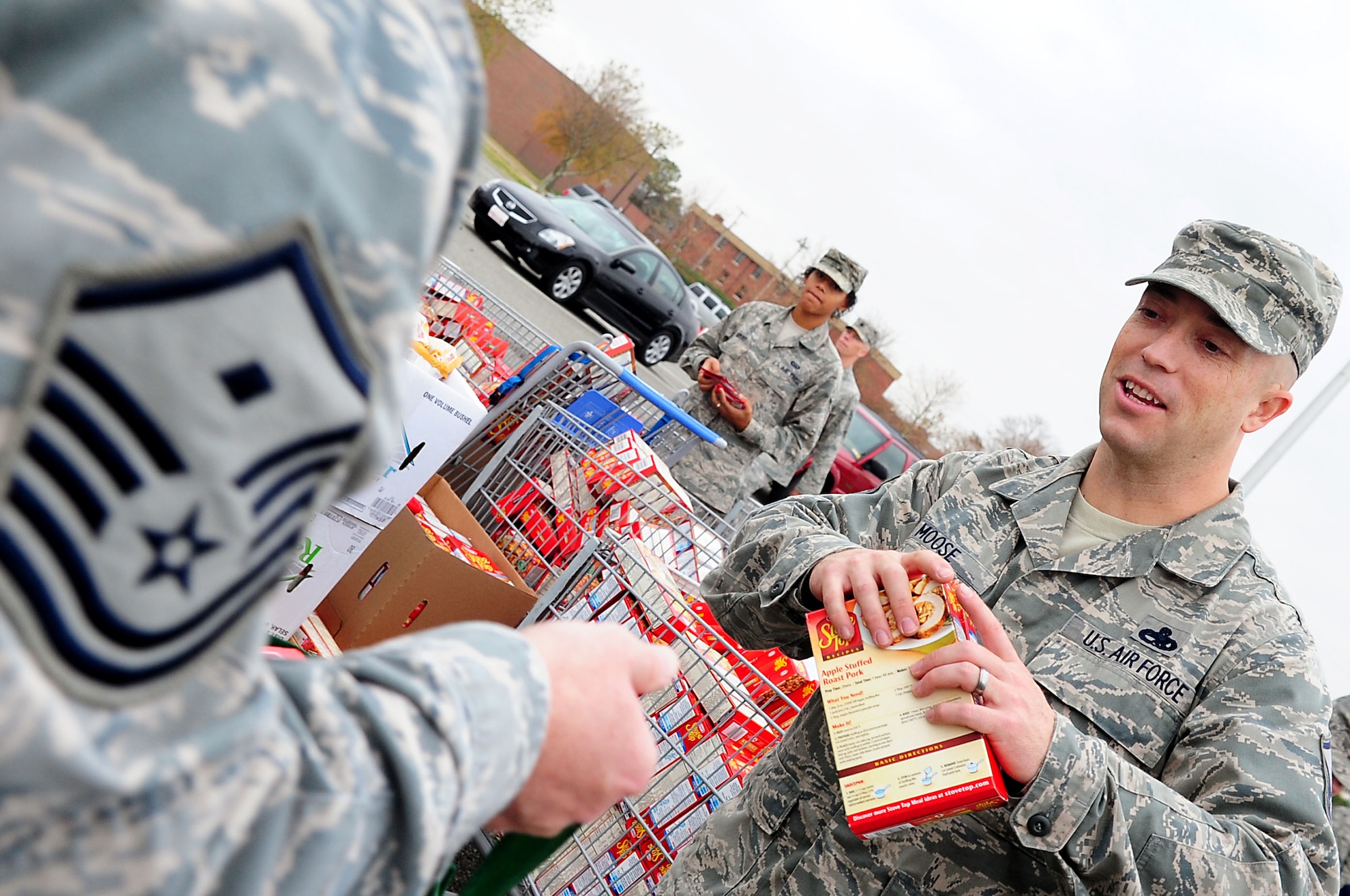 U.S. Air Force Master Sgt. Kelly Moose, 1st Aircraft Maintenance Squadron first sergeant, places a nonperishable food item into the bag of Master Sgt. Shawn Millbaugh, 83rd Network Operations Squadron first sergeant, during Operation Warmheart at Langley Air Force Base, Va., Nov. 21, 2011. First Sergeants coordinate with supervisors to identify Airmen that would benefit most from the baskets that are donated through the Operation Warmheart program.  (U.S. Air Force photo by Airman 1st Class Kayla Newman/Released)
