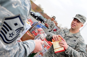 U.S. Air Force Master Sgt. Kelly Moose, 1st Aircraft Maintenance Squadron first sergeant, places a nonperishable food item into the bag of Master Sgt. Shawn Millbaugh, 83rd Network Operations Squadron first sergeant, during Operation Warmheart at Langley Air Force Base, Va., Nov. 21, 2011. First Sergeants coordinate with supervisors to identify Airmen that would benefit most from the baskets that are donated through the Operation Warmheart program.  (U.S. Air Force photo by Airman 1st Class Kayla Newman/Released)