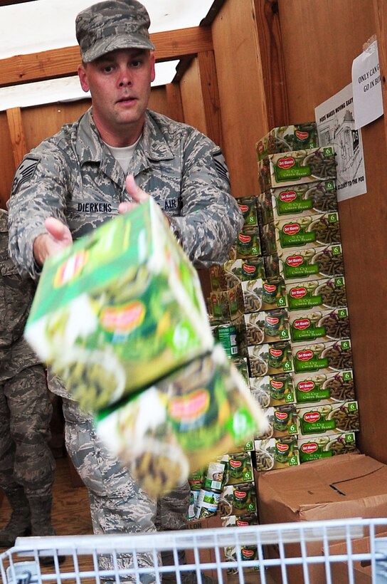U.S. Air Force Master Sgt. Edward Dierkens, 30th Intelligence Squadron first sergeant, throws canned goods into a shopping cart during the Operation Warmheart basket build and distribution kick off at Langley Air Force Base, Va., Nov. 21, 2011. Operation Warmheart provides complete Thanksgiving dinners to eligible junior enlisted Airmen and their families during the holiday season. (U.S. Air Force photo by Airman 1st Class Kayla Newman/Released)