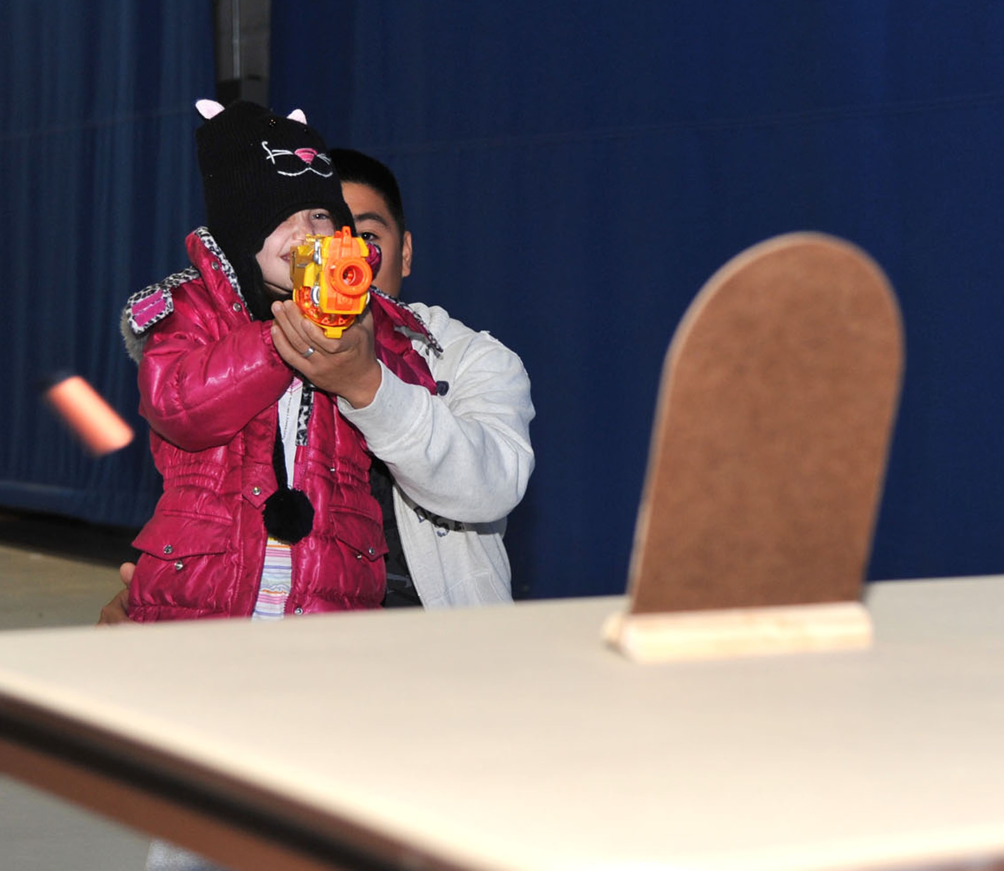 U.S. Air Force Airman 1st Class Jan Tiu, 633rd Logistics Readiness Squadron individual protection equipment technician, assists daughter, Laureana, shoot at a target during Operation Hero at Langley Air Force Base, Va., Nov. 19, 2011. The goal of Operation Hero is to ease the stress of deployments on children and maintain family unity. (U.S. Air Force photo by Airman 1st Class Camilla Griffin/Released)