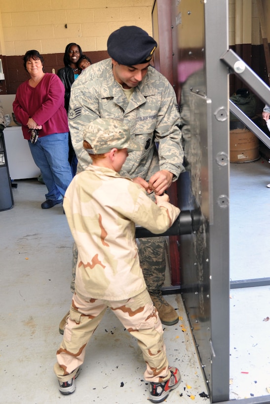 U.S. Air Force Staff Sgt. Paul Sinkuc, 633rd Security Forces Squadron special reaction team NCO in charge, participates in a door breach with Nathan Burkett, son of  U.S. Air Force Maj. Noel Burkett, during Operation Hero at Langley Air Force Base, Va., Nov. 19, 2011. Operation Hero is an annual event designed to help children understand the pre-deployment process; it provides entertainment and hands on activities to allow children the opportunity to experience what their parents do on a daily basis. (U.S. Air Force photo by Airman 1st Class Camilla Griffin/Released)