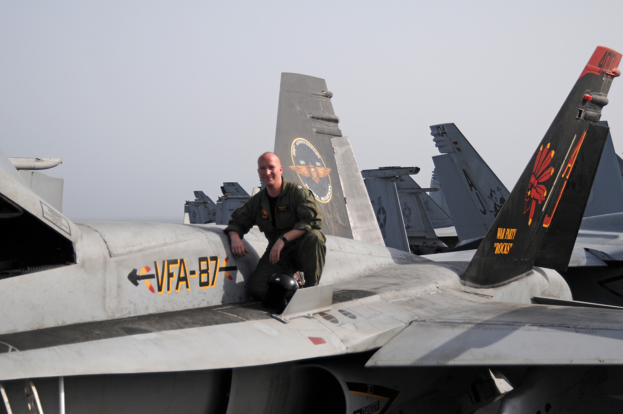 Shown here with F/A-18 Hornet 400 on the flight deck of the USS George H.W. Bush recently is United States Navy Lieutenant Thomas De Jong, native of Orange City, who now flies with Strike Fighter Squadron Eight Seven in the Persian Gulf. (US Navy Photo submitted)