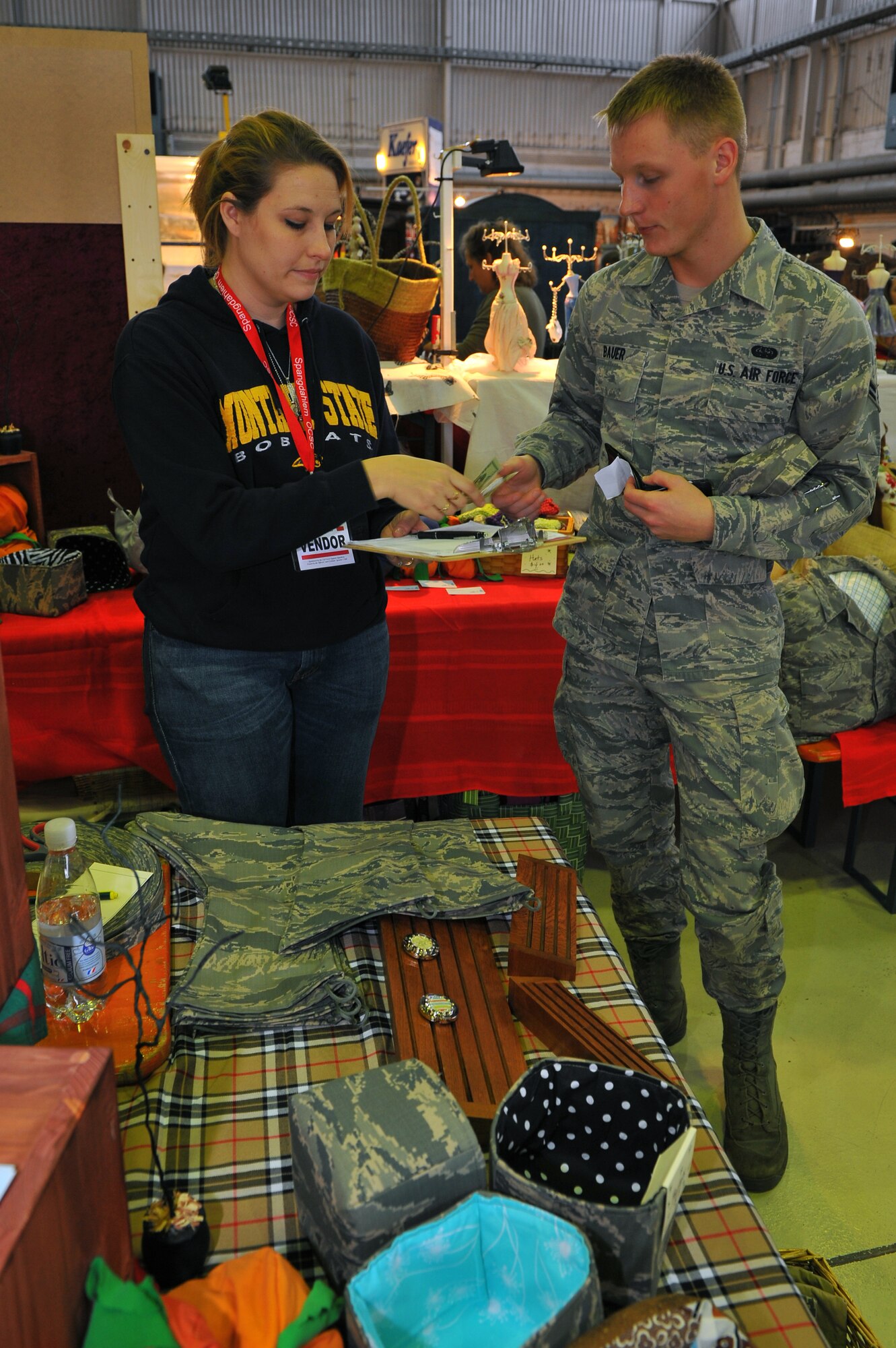 SPANGDAHLEM AIR BASE, Germany – Airman 1st Class Miles Bauer, 606th Air Control Squadron, pays Heather Lewis, wife of Tech Sgt. James Lewis, 52nd Security Forces Squadron, for an Airman Battle Uniform patterned stocking during the fall bazaar here Nov. 18. The Officer and Civilian Spouses Club hosts the bazaar annually, allowing vendors from across Europe to share their products with military members and their families. These products included foodstuffs, furniture and traditional German décor. (U.S. Air Force photo/Airman 1st Class Dillon Davis)