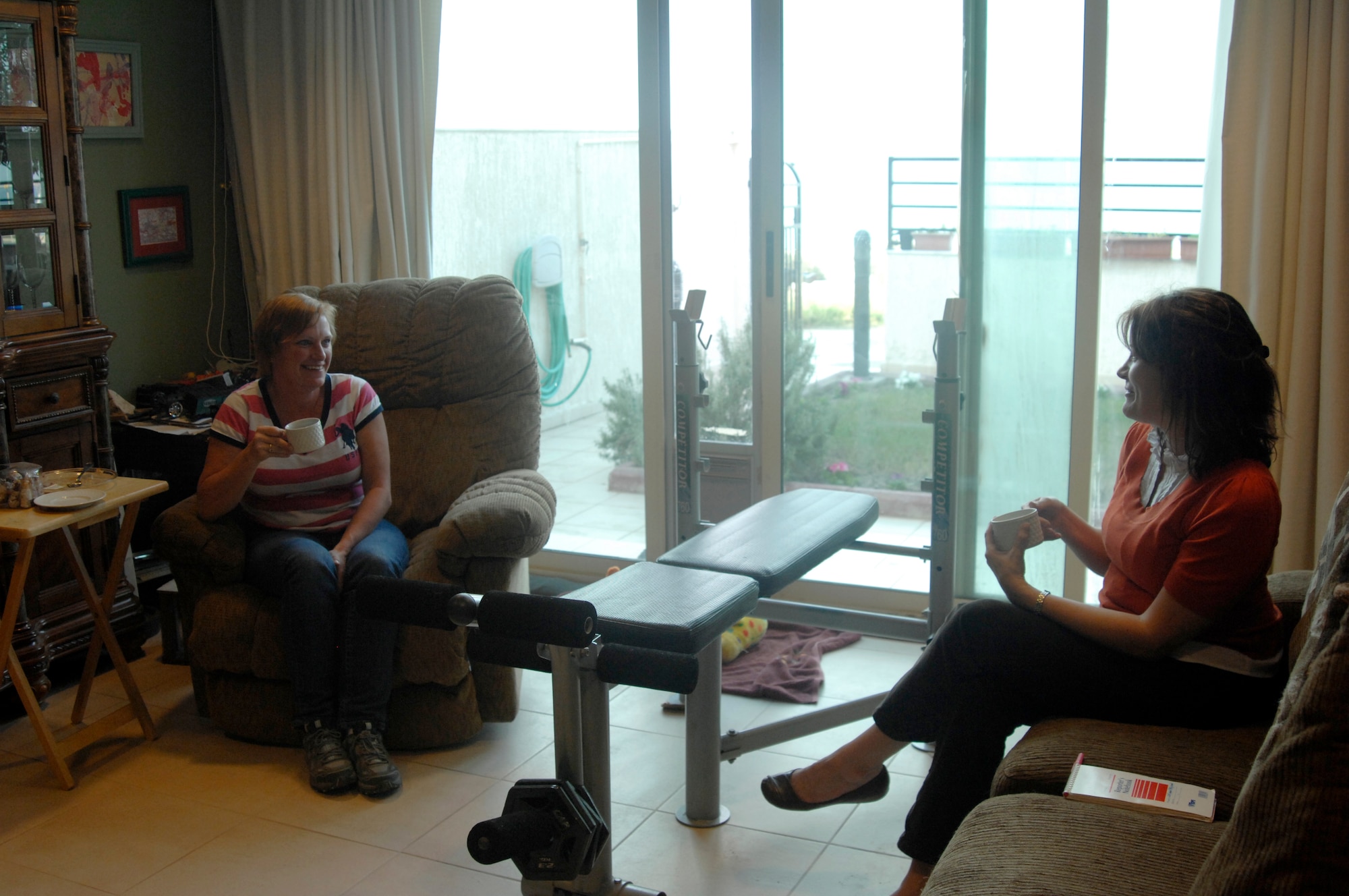 Tech. Sgt. Jami Linn, 467th Air Expeditionary Group executive assistant, has a cup tea with host family member, Allyson Schaff, during a Thanksgiving celebration Nov. 19, 2011, at an undisclosed location in Southwest Asia. Hundreds of service members were provided a traditional Thanksgiving meal provided by expatriates in Southwest Asia. Linn is deployed from Barksdale Air Force Base, La., and is a native of Tahlequah, Okla. (U.S. Air Force photo by Senior Airman Amber R. Kelly-Herard) 