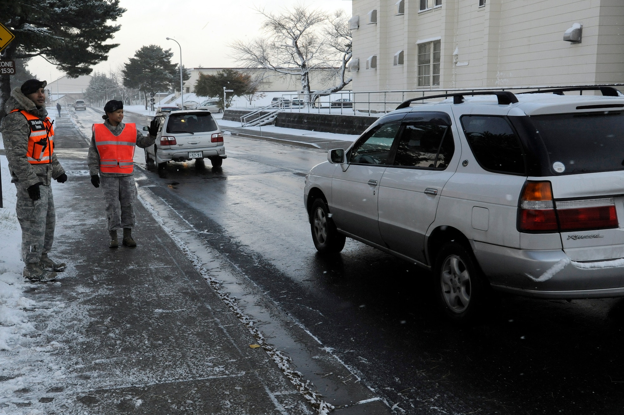 MISAWA AIR BASE, Japan - Staff Sgt. Anthony Santillan, left, and Airman 1st Class Carol Advincula, 35th Security Forces Squadron, observe traffic outside Edgren High School here Nov. 21. Wing leadership is stepping up efforts to get people to slow down around the schools and to obey the posted speed limits. Drivers will lose one day of driving privileges for every kilometer over the posted speed limit if caught speeding around the schools or in base housing areas. (U.S. Air Force photo/Tech. Sgt. Marie Brown)
