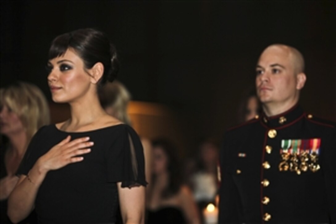 Marine Corps Sgt. Scott Moore, right, and his guest, actress Mila Kunis, stand during the national anthem at the 236th Marine Corps birthday ball for the 3rd Battalion, 2nd Marine Regiment, 2nd Marine Division in Greenville, N.C., Nov. 18, 2011.