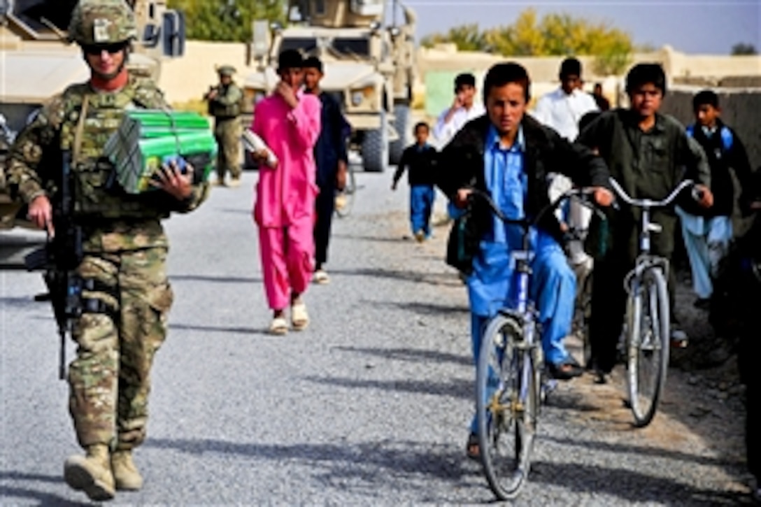 U.S. Navy Lt. j.g. Will Parker, a member of Provincial Reconstruction Team Farah, hands out Sada-e Azadi magazines while other members check on the quality of Nawbahar Road, in the Khak-e Safeyd district in Afghanistan's Farah province, Nov. 16, 2011. The team conducts quality assurance checks on road projects to ensure that contractors meet the construction requirements outlined by the team and government officials.