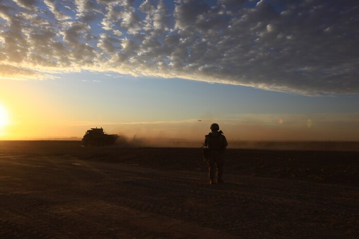 A Marine with Combat Logistics Battalion 1, 2nd Marine Logistics Group (Forward), posts security as construction vehicles carry gravel to a worksite in Helmand province, Afghanistan, Nov. 22. The gravel will be used to build Route Victoria in the coming weeks. (U.S. Marine Corps photo by Cpl. Katherine M. Solano)