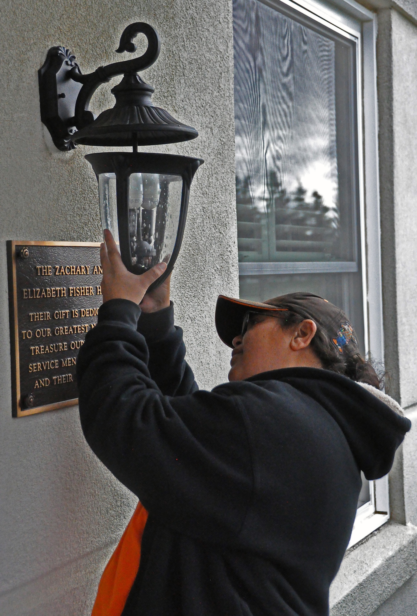Rosetta Bell, merchandise execution team supervisor, replaces the front porch lights Nov. 18 during the remodeling of the Travis Fisher House. (U.S. Air Force photo/Airman Madelyn Ottem)