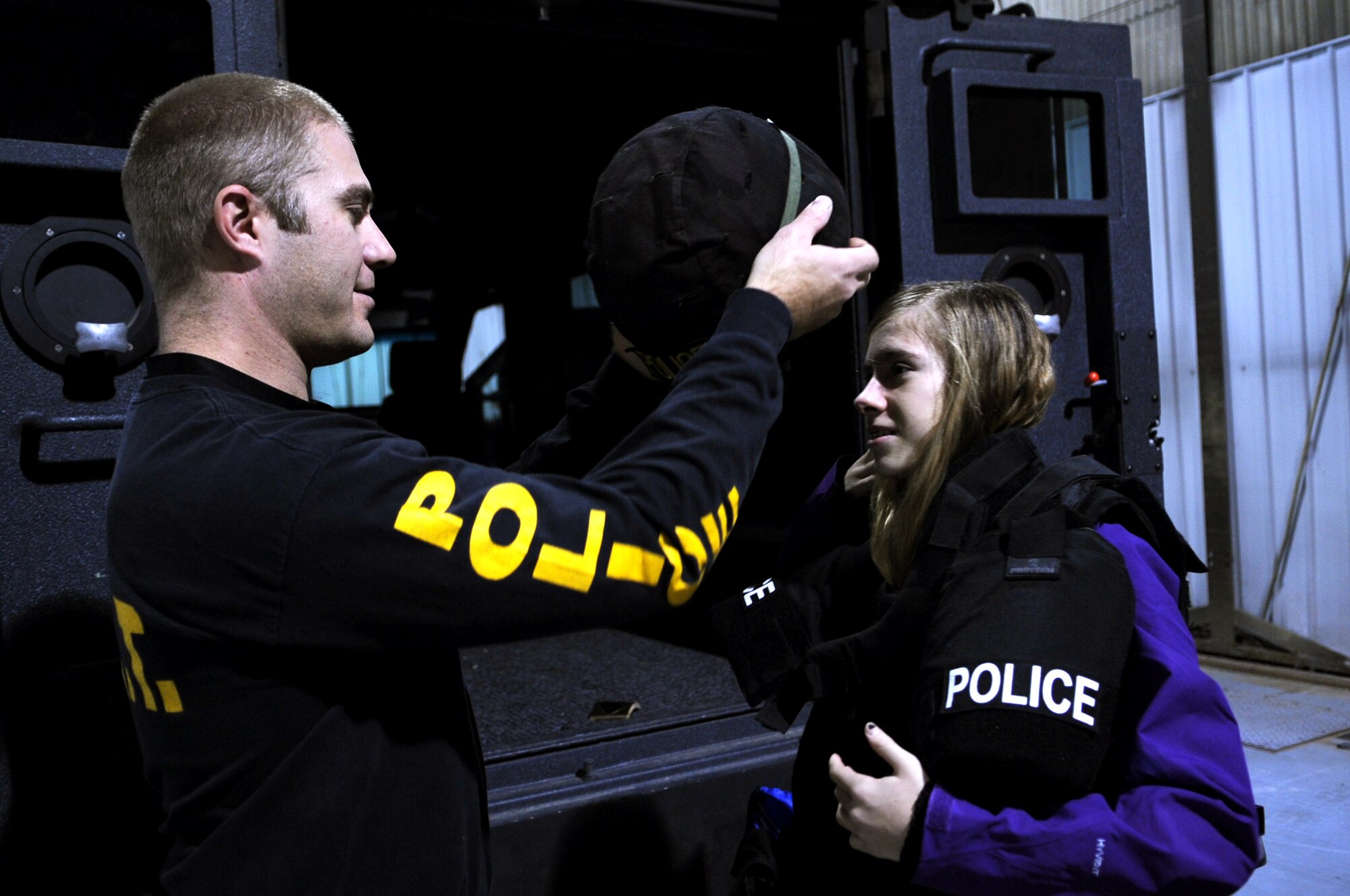 Travis Benson, Grand Forks Police Department, places protective gear on Anna Colasanti, daughter of Lt. Col. Marie Colasanti, 319th Medical Operations Support commander, while processing the line on Grand Forks Air Force Base, N.D., Nov. 19.  The base hosted a deployment line for children of affiliated military families to get a feel of the process when a parent deploys.  (U.S. Air Force photo by Senior Airman Amanda N. Grabiec)