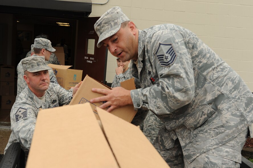 Master Sgt. Matt Stathakis passes a box to Master Sgt. Jeffrey Smith during the Thanksgiving food drive on Seymour Johnson Air Force Base, N.C., Nov. 21, 2011. The First Sergeant's Council packed 270 boxes of collected items for the food drive that went to Airmen who need help during the holiday season. Stathakis is the 4th Medical Group first sergeant and a native of Deerfield Beach, Fl. Smith is the 4th Aircraft Maintenance Squadron tactical section chief from Milford, Conn. (U.S. Air Force photo by Senior Airman Whitney Stanfield)