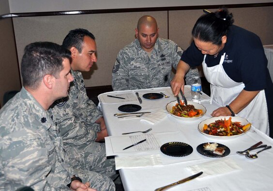 A panel of judges from March Air Reserve Base, Calif., are served pork dishes by Hap Arnold Club head cook, Nam Dodson at round one of a Top Chef competition Nov. 15, 2011.  Dodson is a repeat competitor in the contest.  Judges are Lt. Col. Brice Middleton,  912nd Air Refueling Squadron commander, Tech. Sgt. Javier Murillo and Master Sgt. Christopher Jugas, 452nd Security Forces Squadron.  (U.S. Air Force photo/Linda Welz)