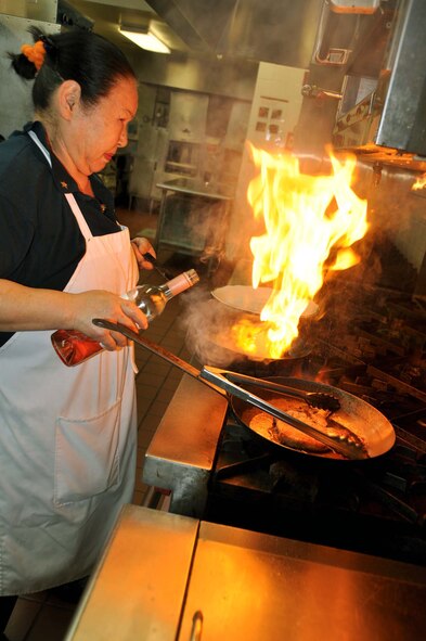 Nam Dodson, Hap Arnold Club head cook,  adds some wine to create a glaze for one of her pork dishes Nov. 15, 2011, during a chef competition at March Air Reserve Base, Calif.  Cooks were given four ingredients, a specific cooking method and 45 minutes to prepare a dish.  (U.S. Air Force photo/Linda Welz)
