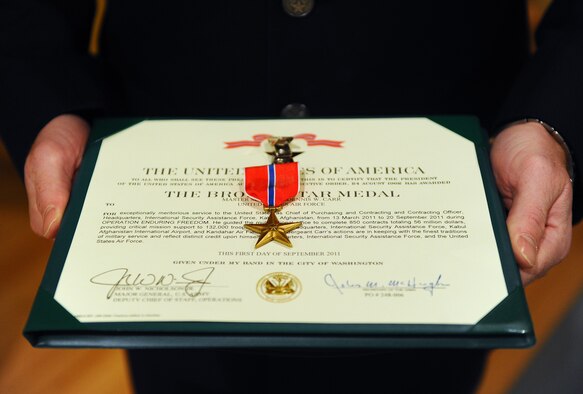 The Bronze Star Medal being awarded to Master Sgt. Dennis W. Carr, 55th Contracting Squadron, rests on the certificate before being presented at a formal ceremony held at the base theater on Offutt Air Force Base, Neb., Nov. 21. Carr received the Bronze Star for providing critical mission support to more than 130,000 troops while deployed to the Kabul Afghanistan International Airport, and Kandahar Air Field. (U.S. Air Force photo by Josh Plueger/Released).