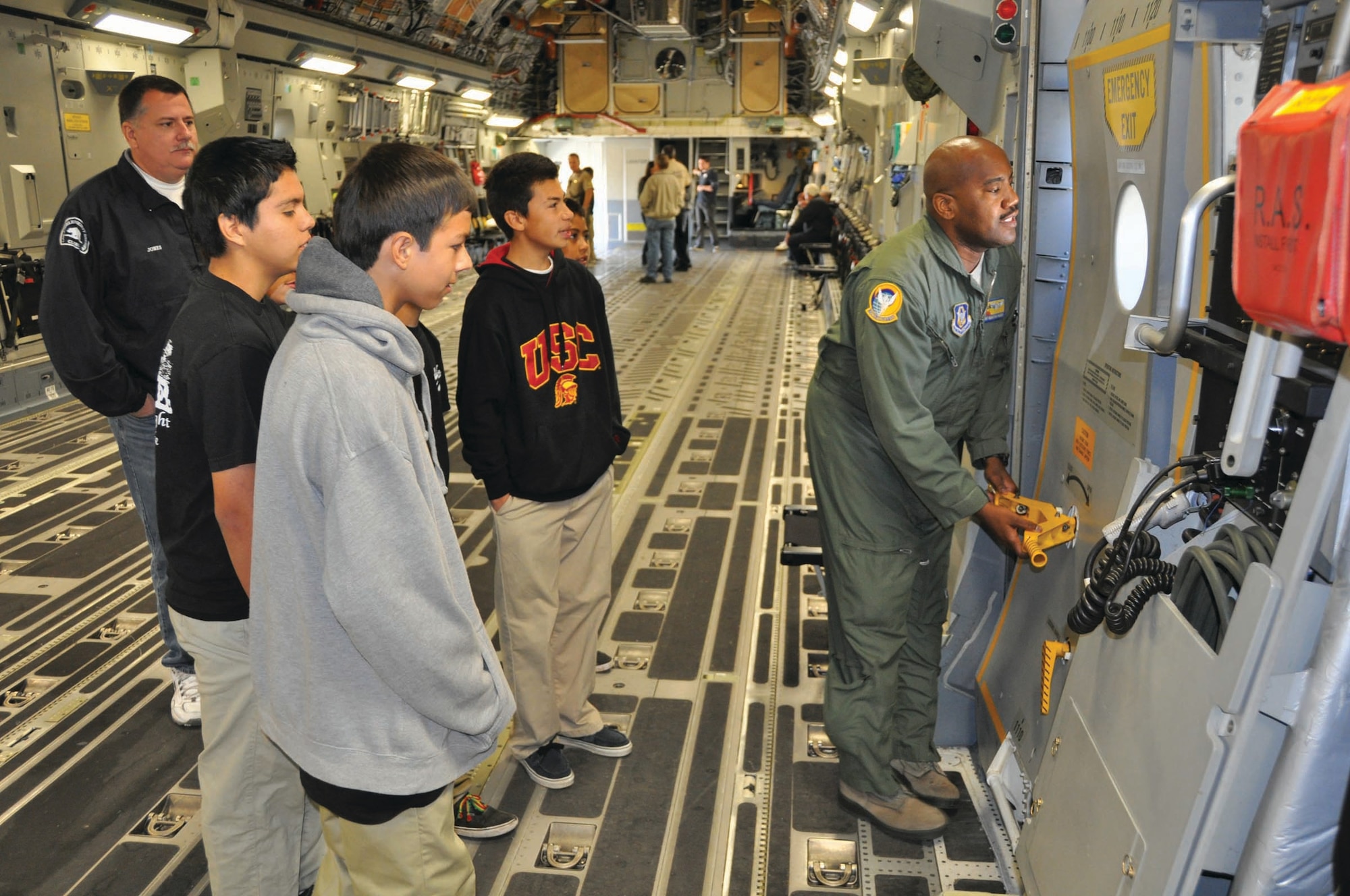 Master Sgt. Sebastian Faison, a loadmaster with the 729th Airlift Squadron, demonstrates how to open the side door of a C-17 Globemaster III to teens enrolled in the Norwalk Sheriff's Department's PRIDE program. The teens toured March Air Reserve Base, Calif., on Nov. 5, 2011. (U.S. Air Force photo/Staff Sgt. Megan Crusher)