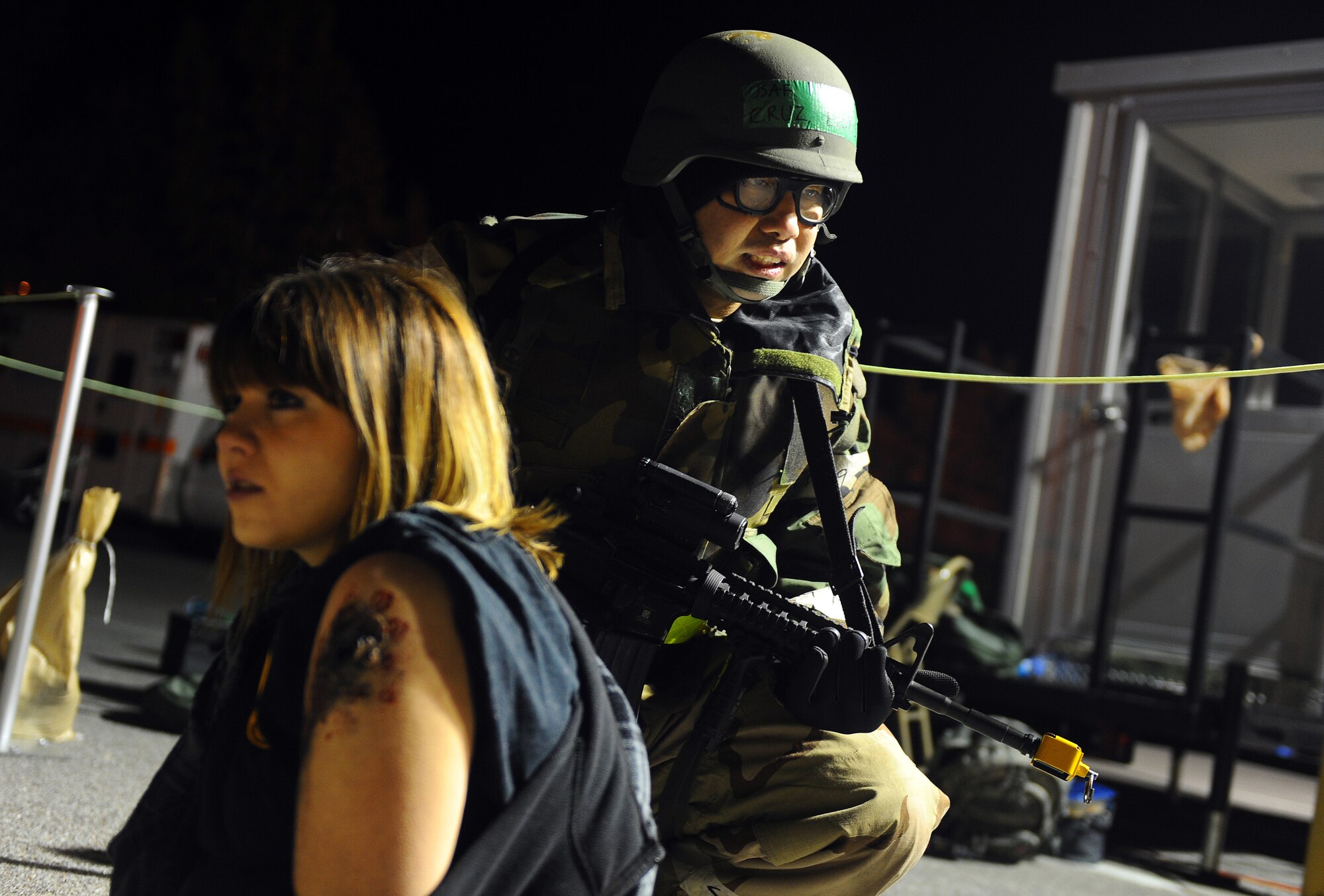 U.S. Air Force Tech. Sgt. Elexis Cruz, 55th Medical Group, protects a woman with a simulated gunshot wound as part of the operational readiness exercise. Cruz maintained vigilance until the area was cleared of enemies at Offutt Air Force Base, Neb., Nov. 15.  These simulated tests prepare Airmen to handle real world events while deployed. (U.S. Air Force photo by Josh Plueger/Released)