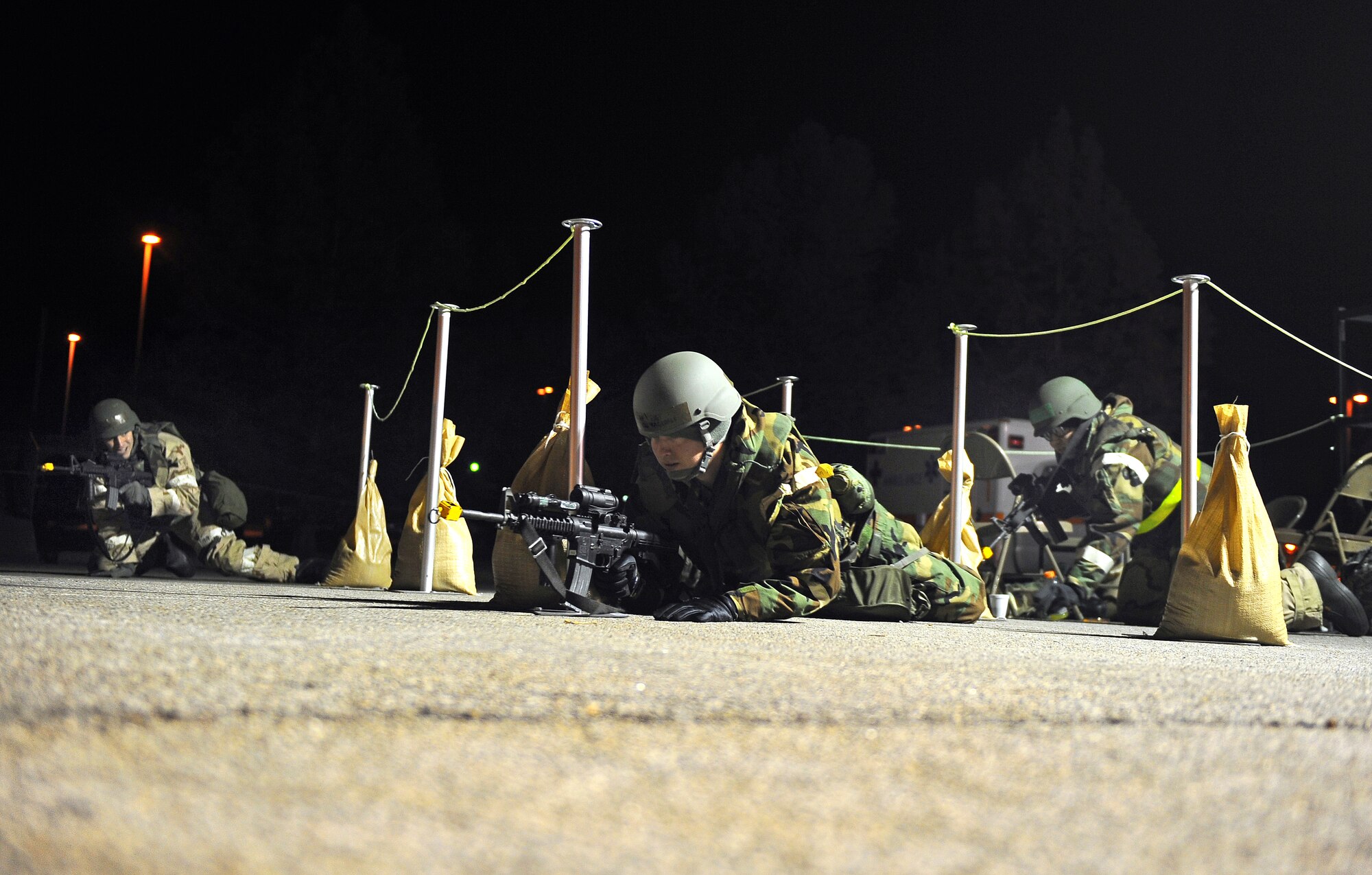 U.S. Air Force Airmen take cover as they come under simulated gun fire while performing entry control duties as part of an operational readiness exercise at Offutt Air Force Base, Neb., Nov. 15.  Airmen with the 55th Wing underwent three consecutive nights of simulated injuries, attacks and chemical warfare scenarios to prepare them for missions at deployed locations around the world. (U.S. Air Force photo by Josh Plueger/Released)