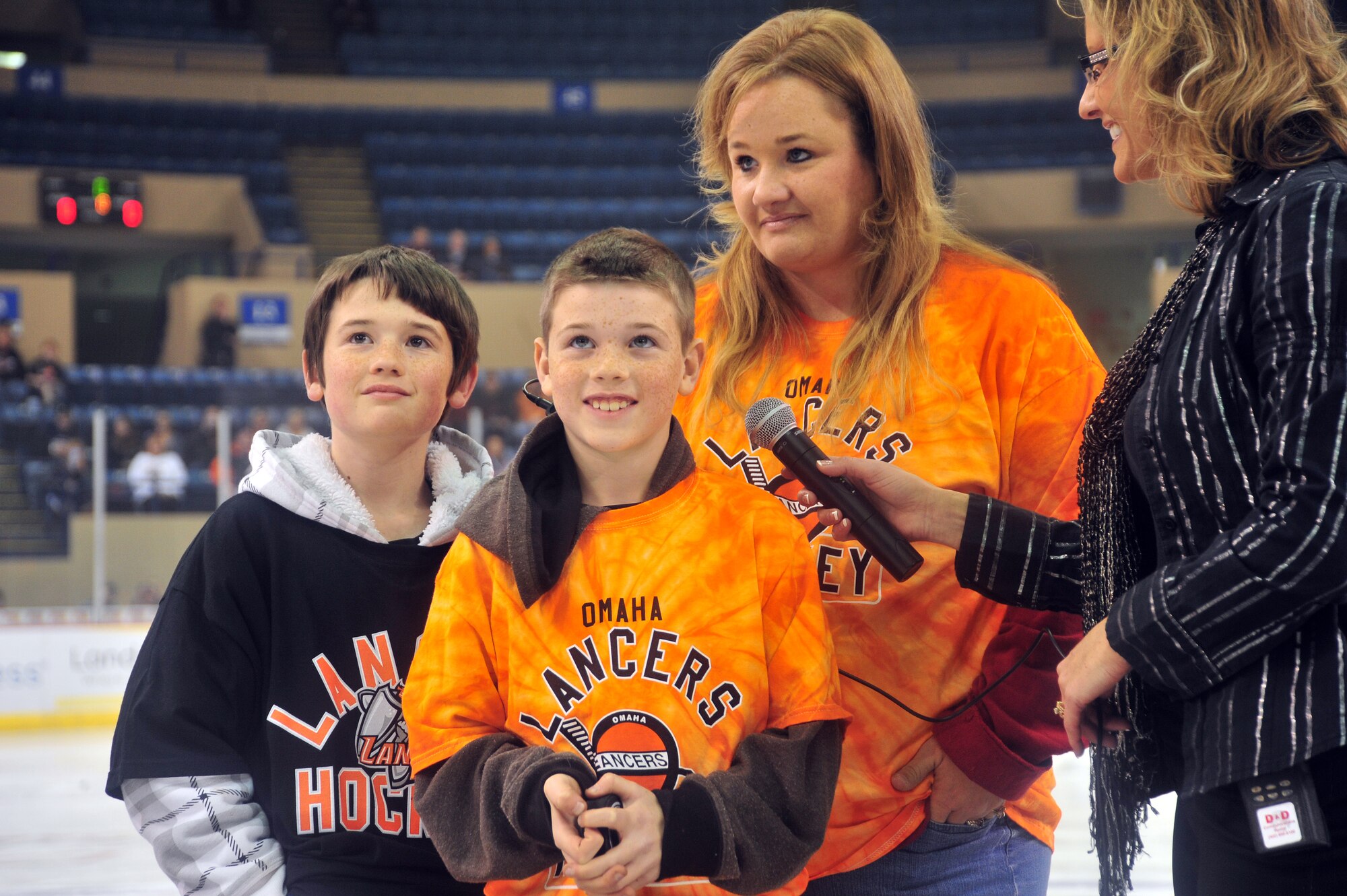 Gregory, Isaac and Krista Peterson, family of deployed Master Sgt. James Peterson, 55th Aircraft Maintenance Squadron, prepares to throw out the first puck for an Omaha Lancers hockey game at the Omaha Civic Auditorium in Omaha, Neb Nov. 11.  The family also got to speak with James on the big screen as part of a Veterans Day salute.
