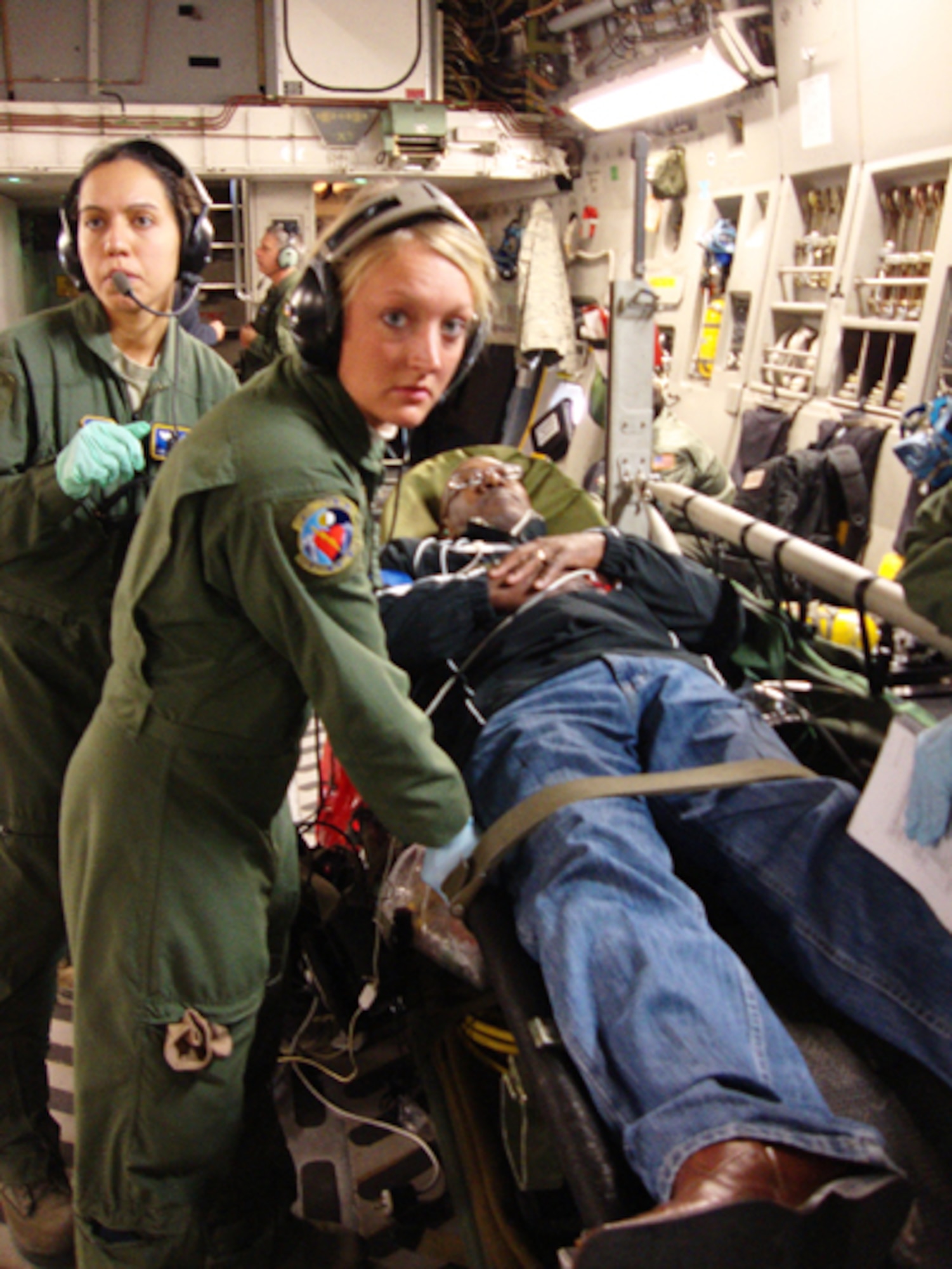 Senior Airmen Ginnette Lykins (left) and Elyse Detling, both medical technicians assigned to the 445th Aeromedical Evacuation Squadron here, listen intently as they receive instructions after securing a simulated patient to a litter during a training flight on board a C-17 Globemaster III Nov. 17. The "volunteer" heart attack victim was James Chappel, a member of the Air Force Materiel Command Community Liaison Program, representing Tinker AFB, Okla. Twenty-one members of the group flew on the C-17 to experience first-hand how members of the squadron train for real-world missions. (U.S. Air Force photo/Ron Fry)
