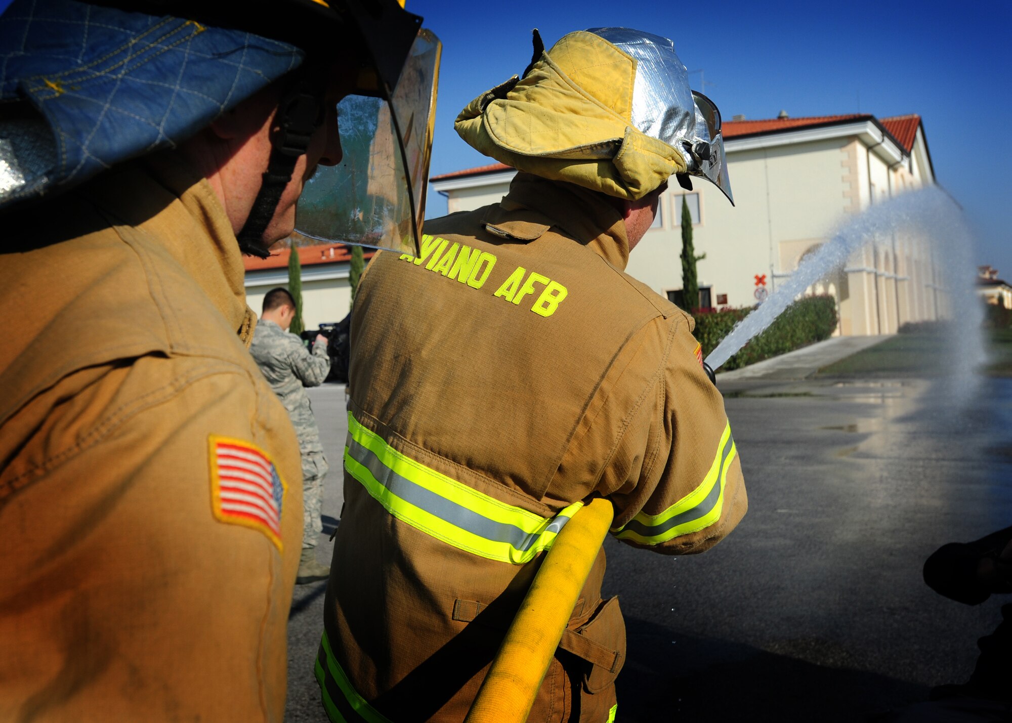 (From Left) Tech. Sgt. Jeremiah Dowling, 31st Civil Engineer Squadron firefighter, and a Slovenian firefighter spray a water hose during a training exercise Nov. 19 at Aviano Air Base, Italy.  The 31st Civil Engineer Squadron firefighters performed an F-16 Fighting Falcon aircraft egress procedures and familiarization training with Slovenian firefighters. (U. S. Air Force Photo/Senior Airman Evelyn Chavez)