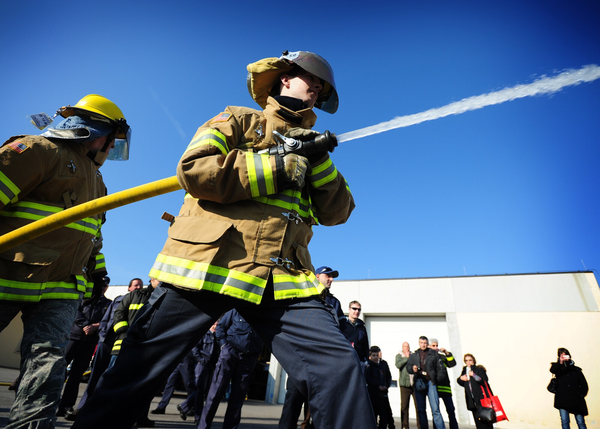 (From Left) Tech. Sgt. Jeremiah Dowling, 31st Civil Engineer Squadron firefighter, and Darko Ferluga, a Slovenian firefighter, spray a water hose during a training exercise Nov. 19 at Aviano Air Base, Italy.  The firefighters performed an F-16 Fighting Falcon aircraft egress procedures and familiarization training with Slovenian firefighters. (U. S. Air Force Photo/Senior Airman Evelyn Chavez)
