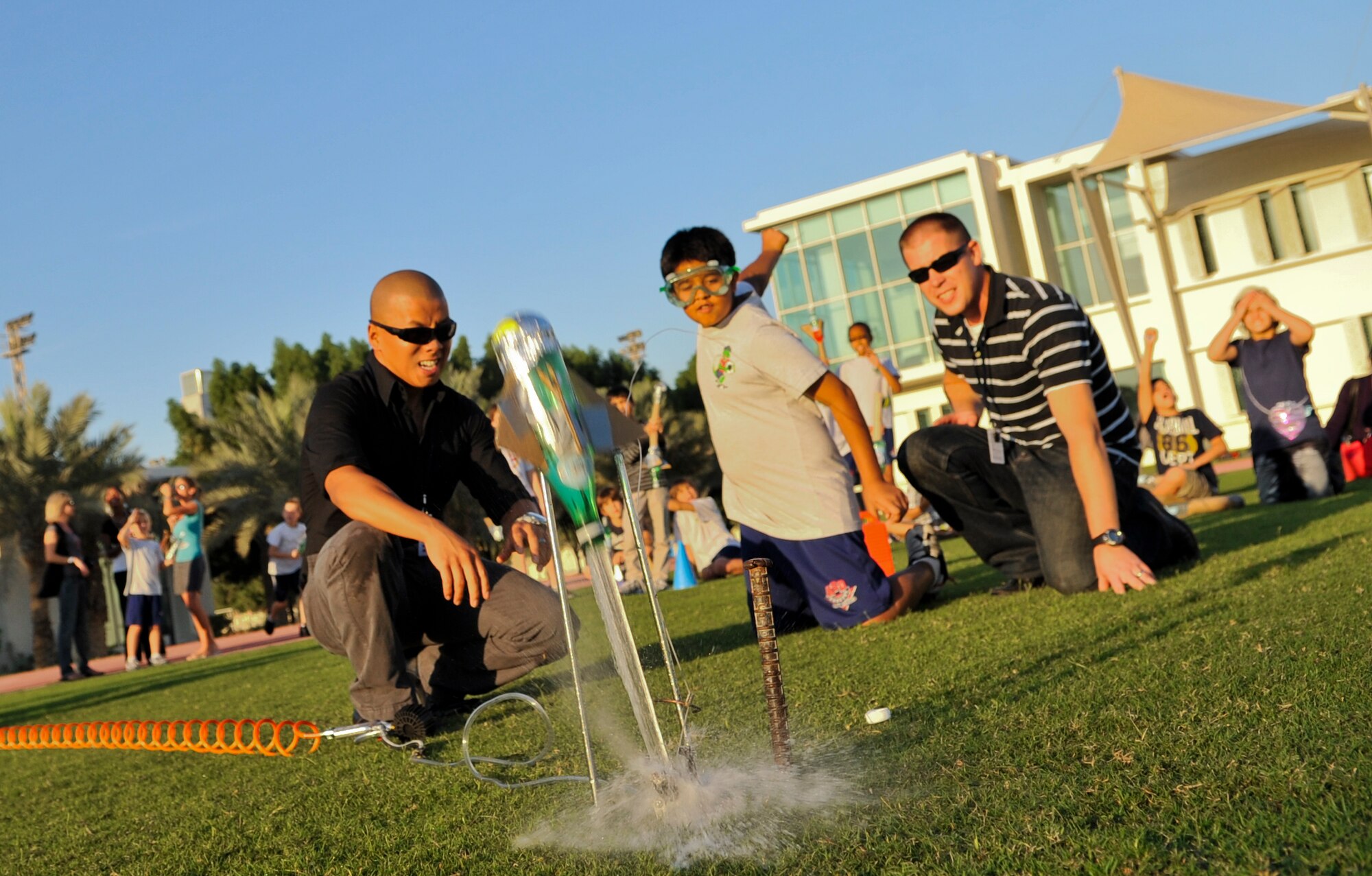 Airman 1st Class Zongtag Vang, 379th Expeditionary Civil Engineer Squadron water and fuel maintenance technician (left) and Tech. Sgt. Kyle Tecmire, U.S. Air Forces Central Command cyber transport technician, help a student from a local school release a water-propelled rocket into the air Nov. 20 at an undisclosed location in Southwest Asia. Each of the 20 students launched hand-built rockets crafted out of water bottles, cardboard and duct tape as part of the Science and Technology Advancement and Relationships (STARS) program. Vang, a native of Kansas City, Kan., is deployed from Yokota Air Base, Japan, while Tecmire, a native of Medford, Ore., is deployed from Kingsley Field, Ore.(U.S. Air Force photo/Senior Airman Paul Labbe)