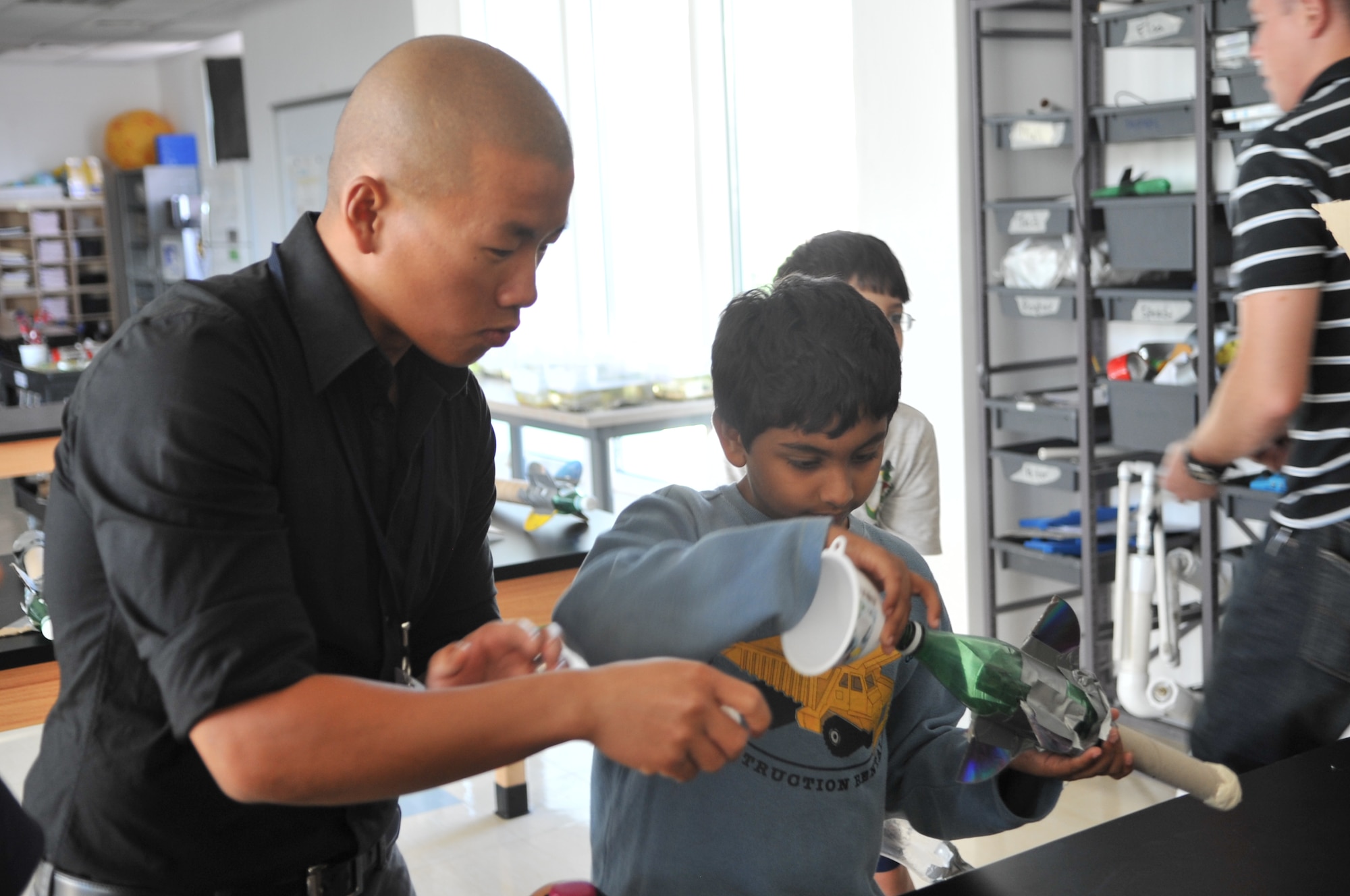 Airman 1st Class Zongtag Vang, 379th Expeditionary Civil Engineer Squadron water and fuel maintenance technician, helps a student from a local school build a water-propelled rocket Nov. 20 at an undisclosed location in Southwest Asia. Each of the 20 students launched hand-built rockets crafted out of water bottles, cardboard and duct tape as part of the Science and Technology Advancement and Relationships (STARS) program. Vang, a native of Kansas City, Kan., is deployed from Yokota Air Base, Japan. (U.S. Air Force photo/Senior Airman Paul Labbe)
