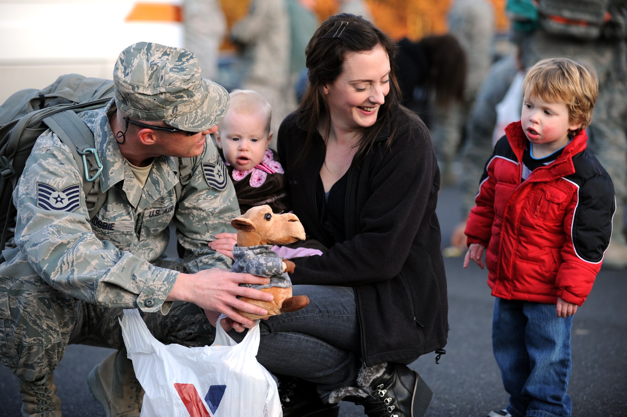 SPANGDAHLEM AIR BASE, Germany – Tech. Sgt. Christopher Crosbie, NCO in charge of the 606th Air Control Squadron maintenance operations center, holds a present out for his son as he is welcomed home by his wife, Amanda, and children,  Beth and Ryan, here Nov. 21. Airmen from the 606th ACS returned from Iraq and were welcomed home by family and fellow service members at Bldg. 340. The squadron deployed to control airspace by maintaining a deployable radar site, satellite communications and ground-to-air radios. (U.S. Air Force photo/Airman 1st Class Matthew B. Fredericks)
