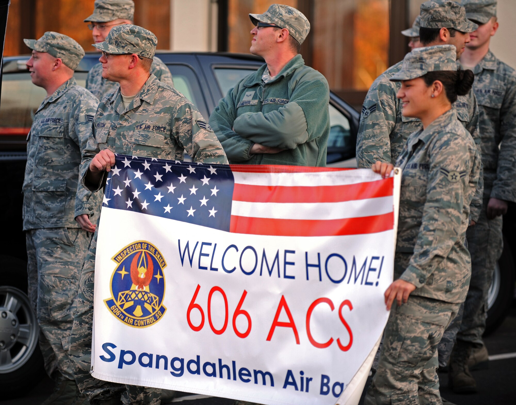 SPANGDAHLEM AIR BASE, Germany – Airmen from the 606th Air Control Squadron hold up a sign welcoming home fellow squadron members here Nov. 21. Airmen from the 606th ACS returned from Iraq and were also welcomed home by family members at Bldg. 340. The squadron deployed to control airspace by maintaining a deployable radar site, satellite communications and ground-to-air radios. (U.S. Air Force photo/Airman 1st Class Matthew B. Fredericks)
